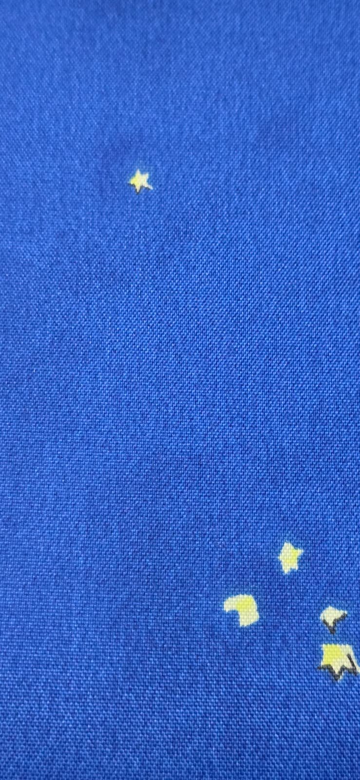 Blue fabric with yellow star-shaped and moon-shaped confetti scattered across it.