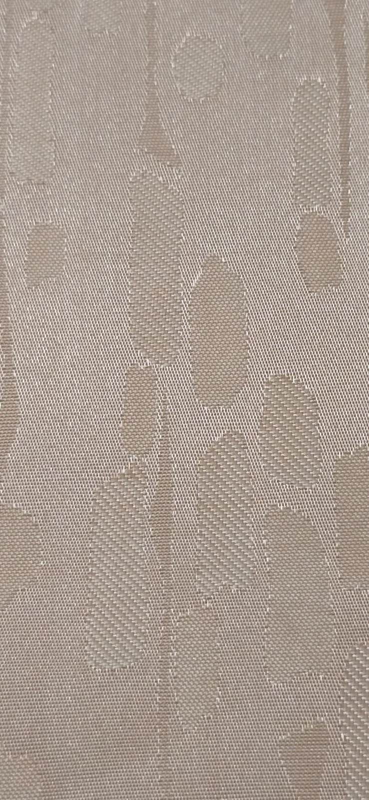 Close-up of a beige fabric with a floral damask pattern woven into it.
