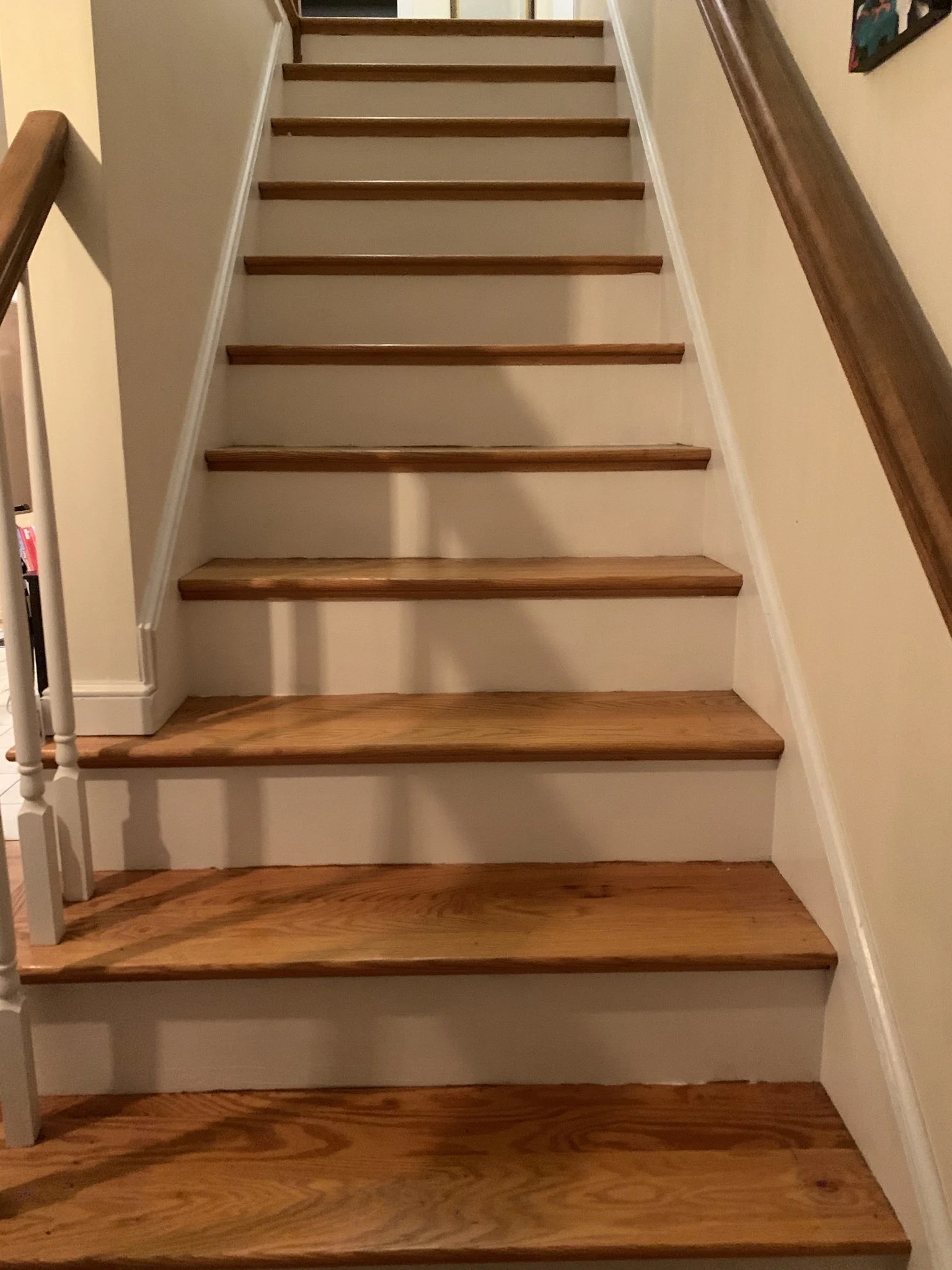Wooden staircase with white risers and handrails on both sides.