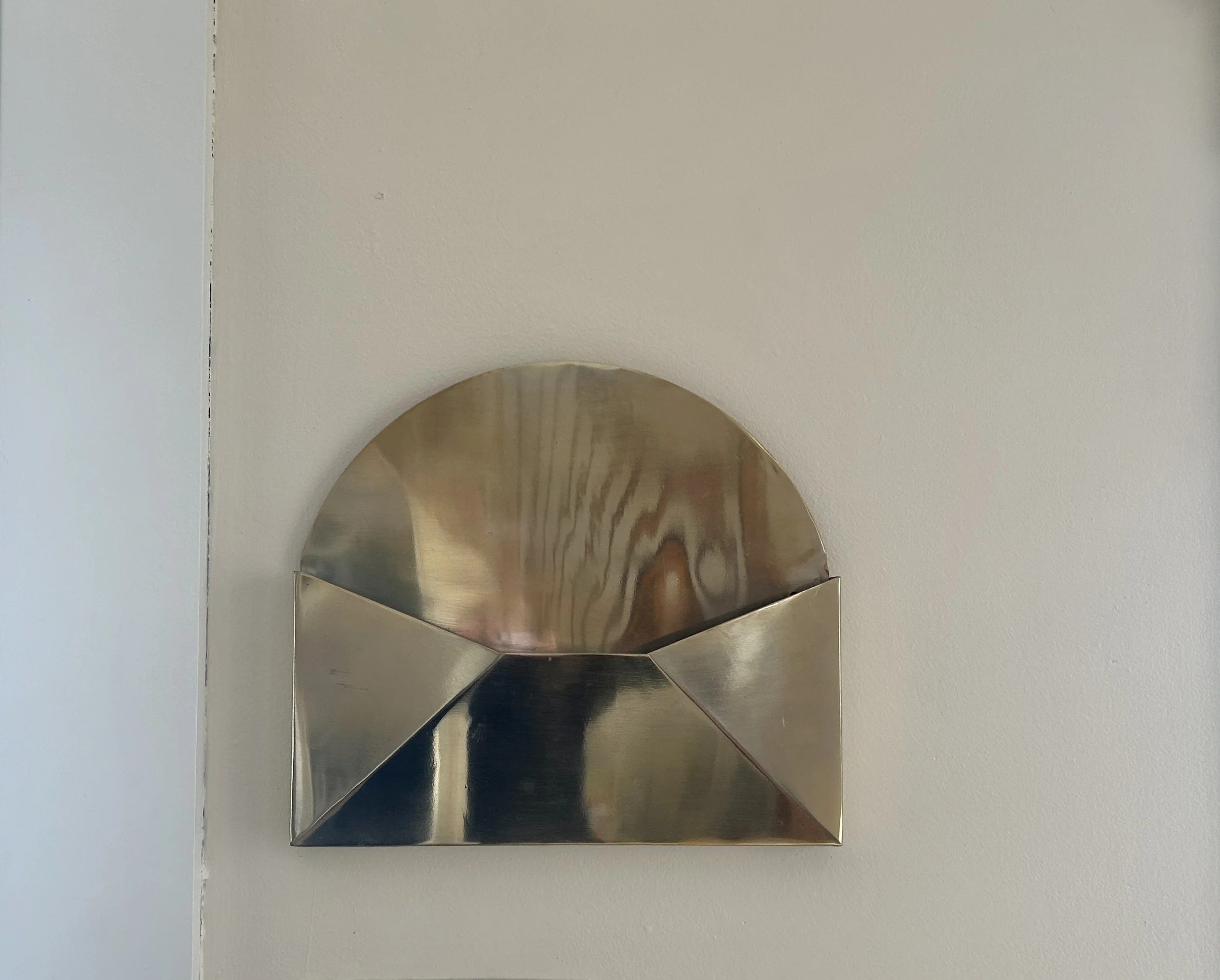 A metallic wall-mounted magazine holder with a semi-circular top and open front.