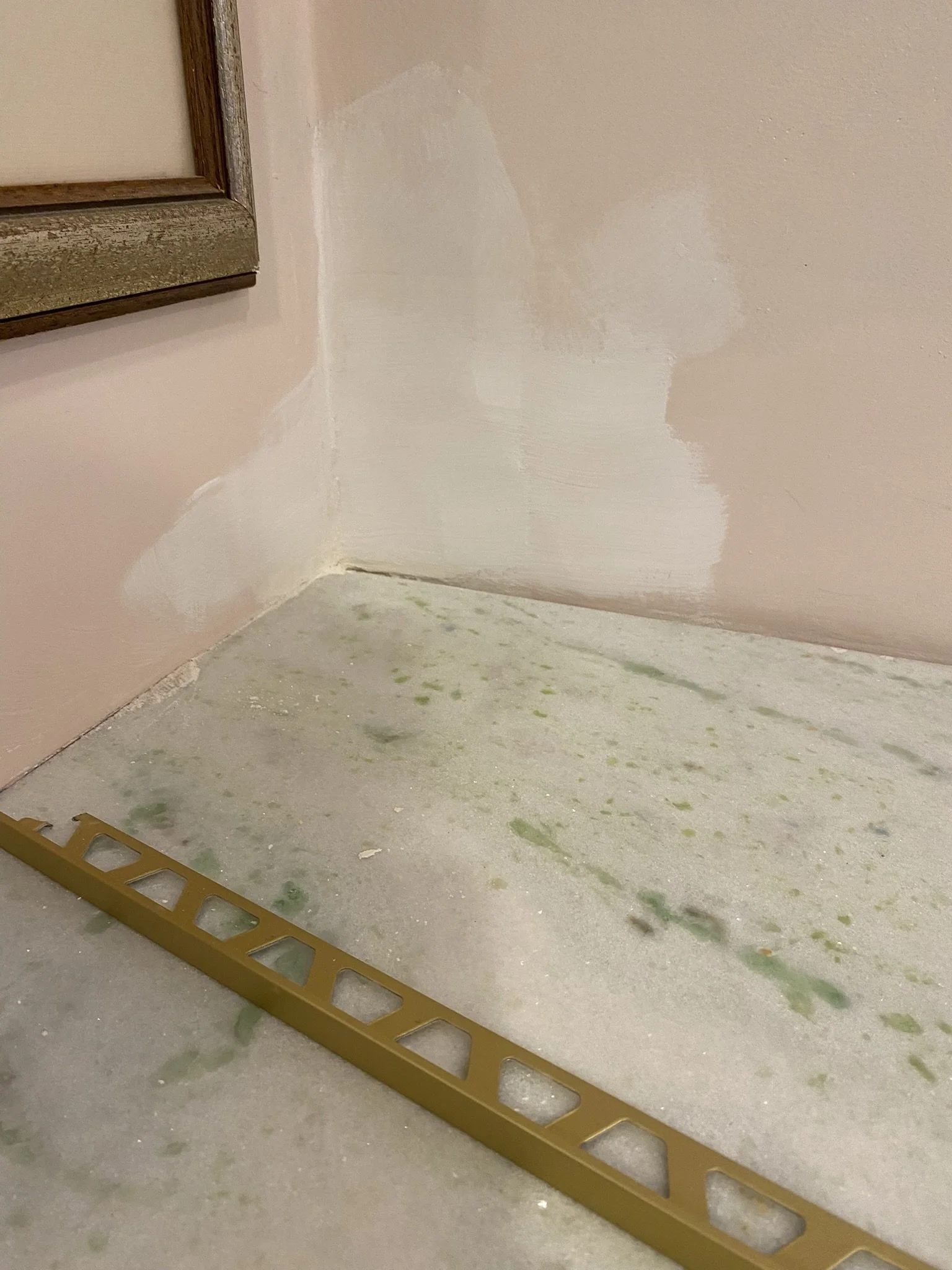 Corner of a room under renovation with drywall, a leveler tool on the floor, and a partially painted wall.