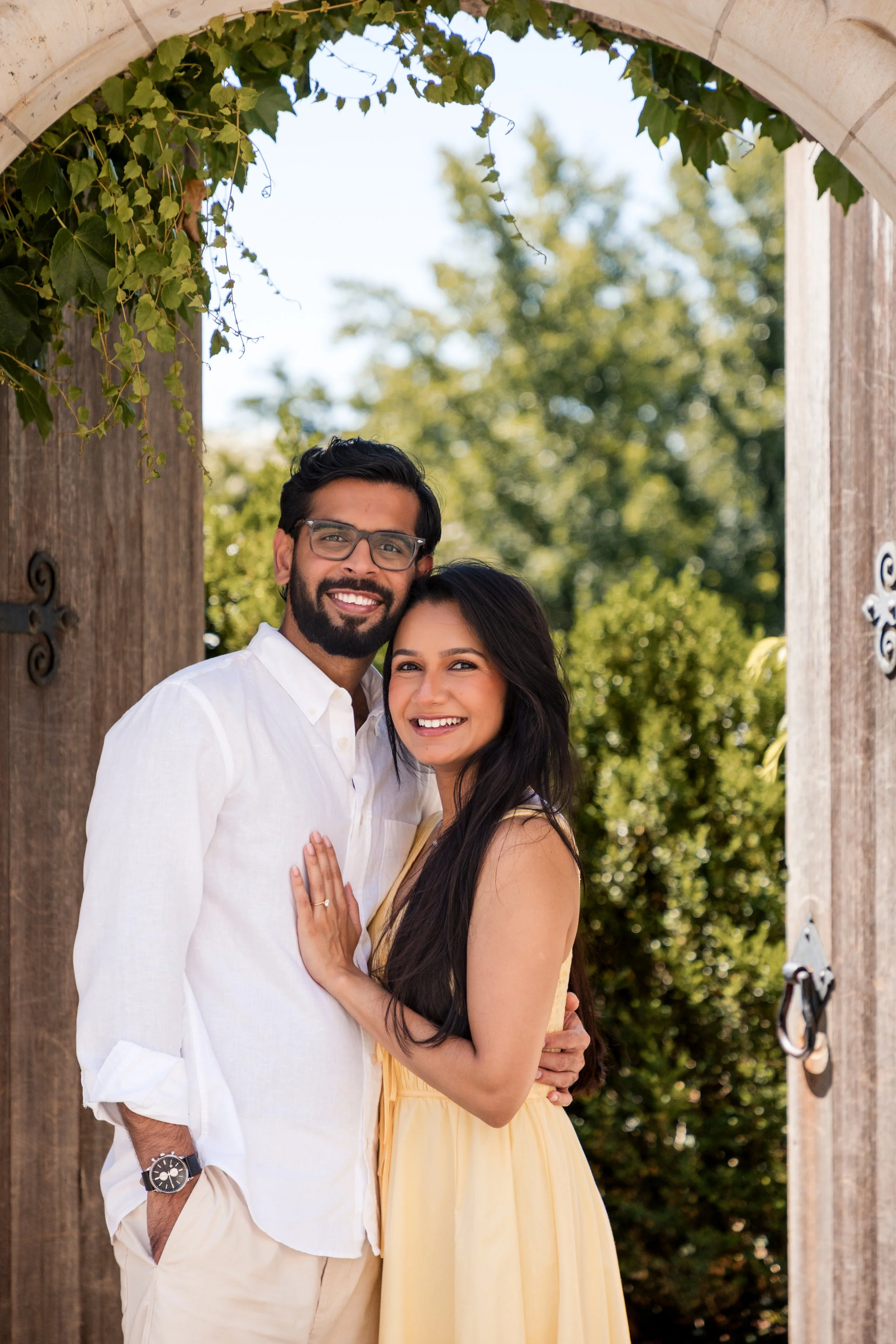 Engaged couple smiling together under a garden arbor, Maryland engagement photography