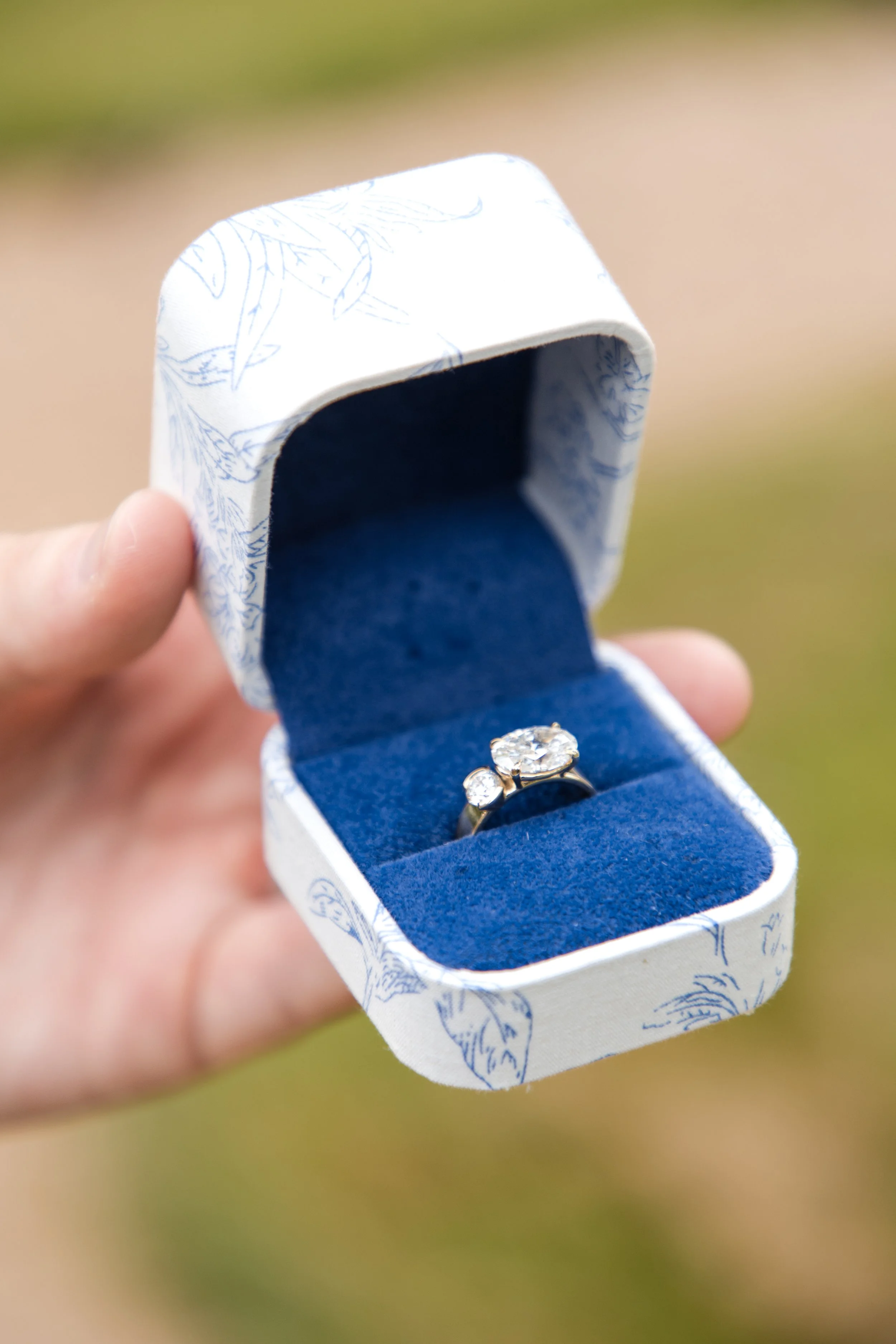 Engagement ring in a blue velvet box held outdoors
