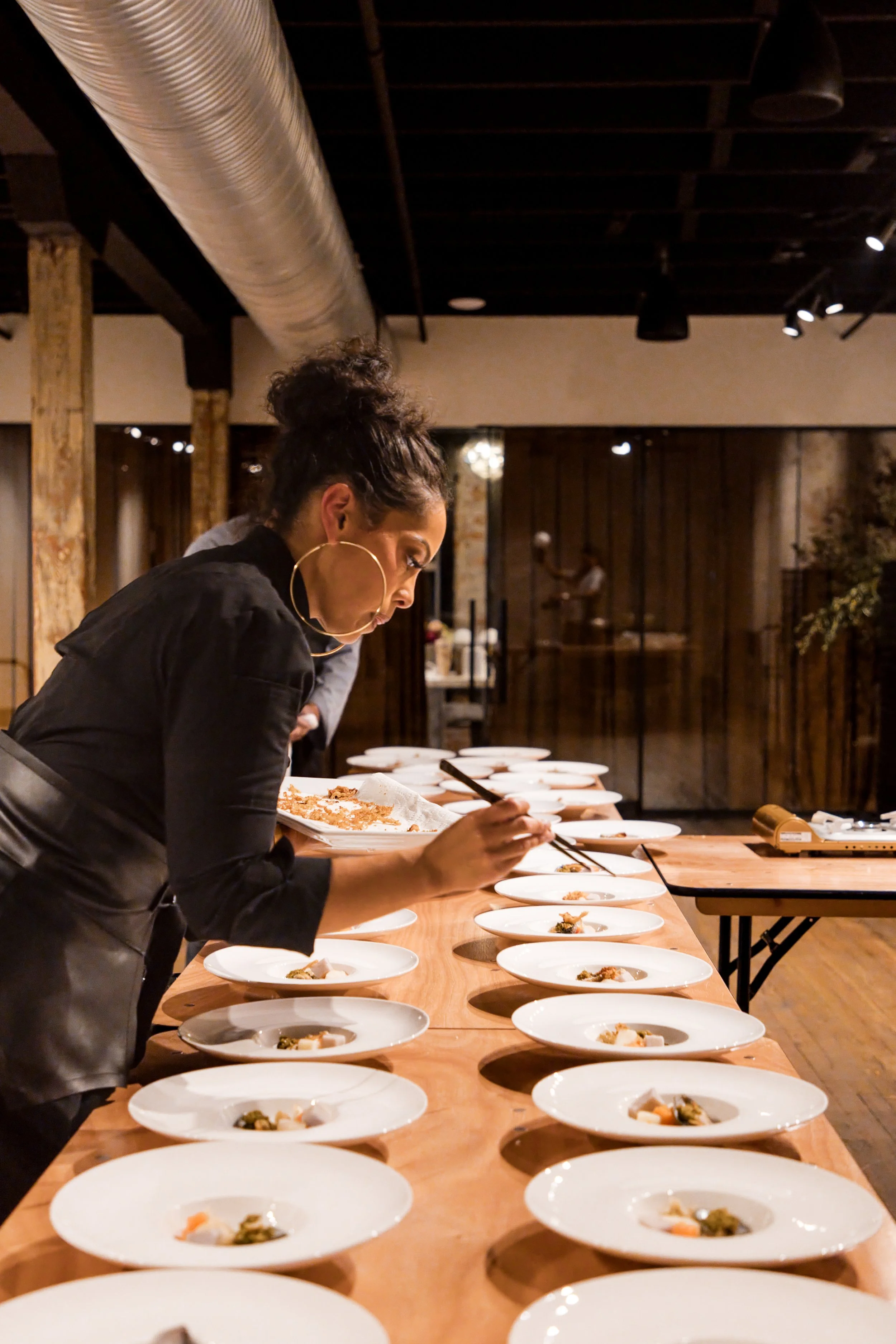 Chef arranging plated courses along a long table before dinner service