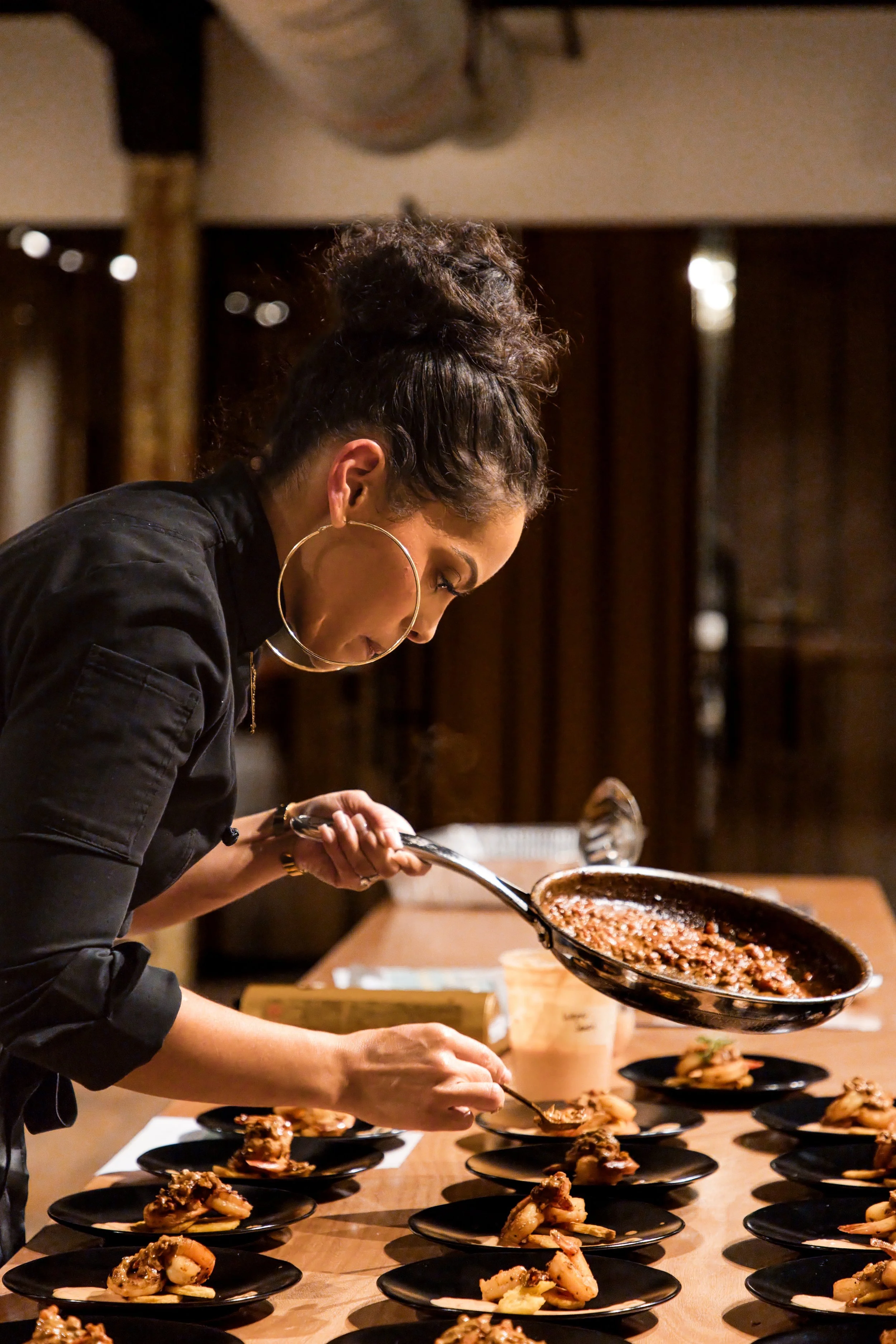 Chef plating dishes in a pan during a private dinner event