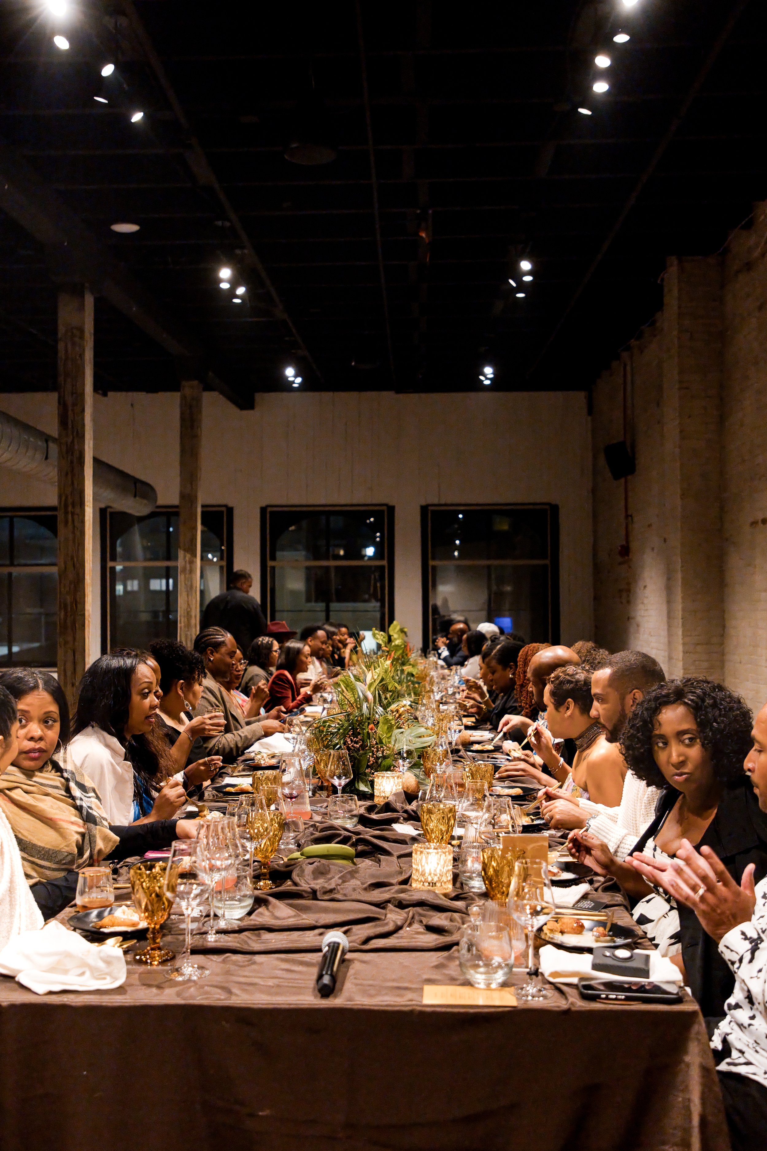 Guests seated along a long candlelit dinner table at a private dinner event