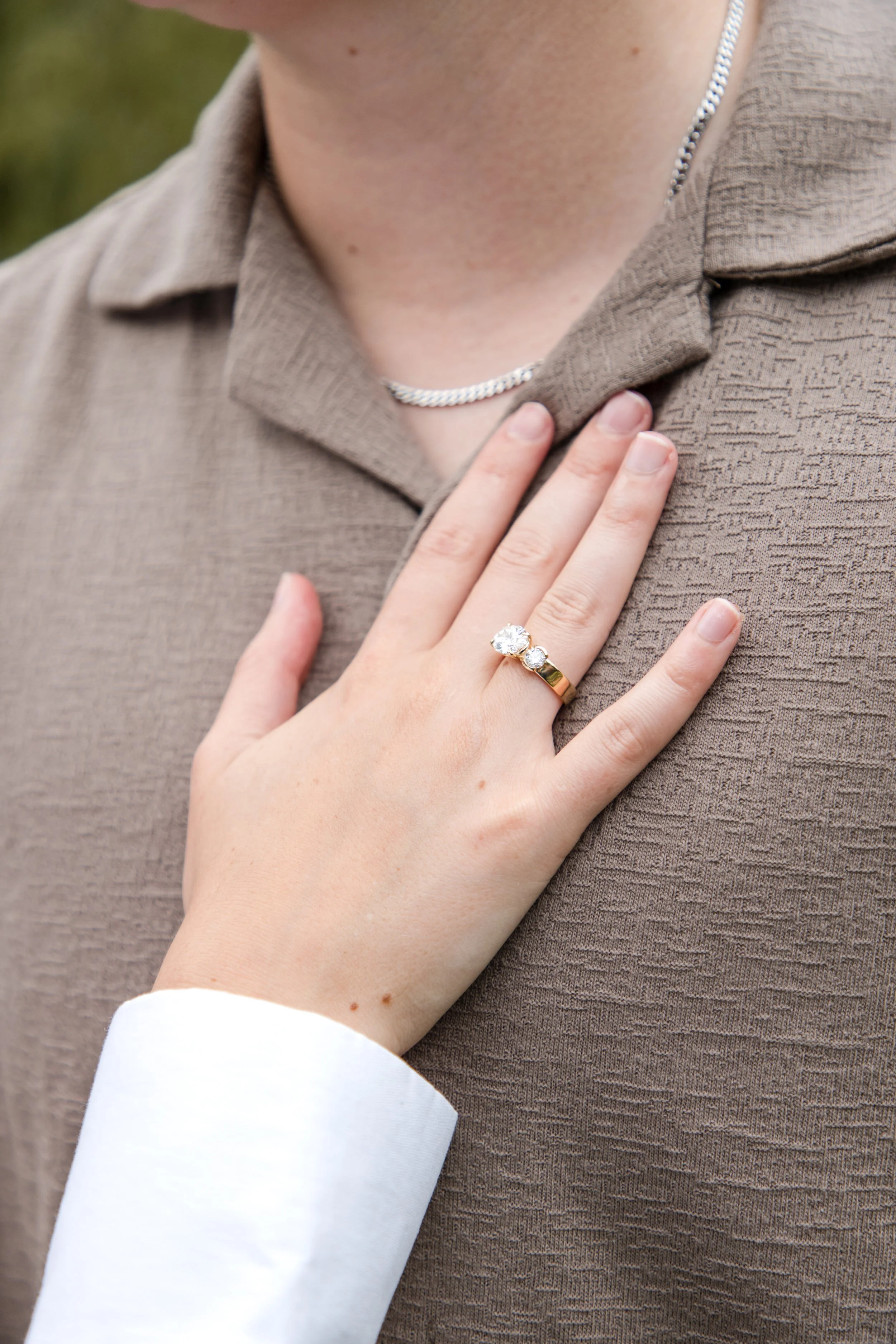 Engagement ring close-up on a hand resting against a partner's chest