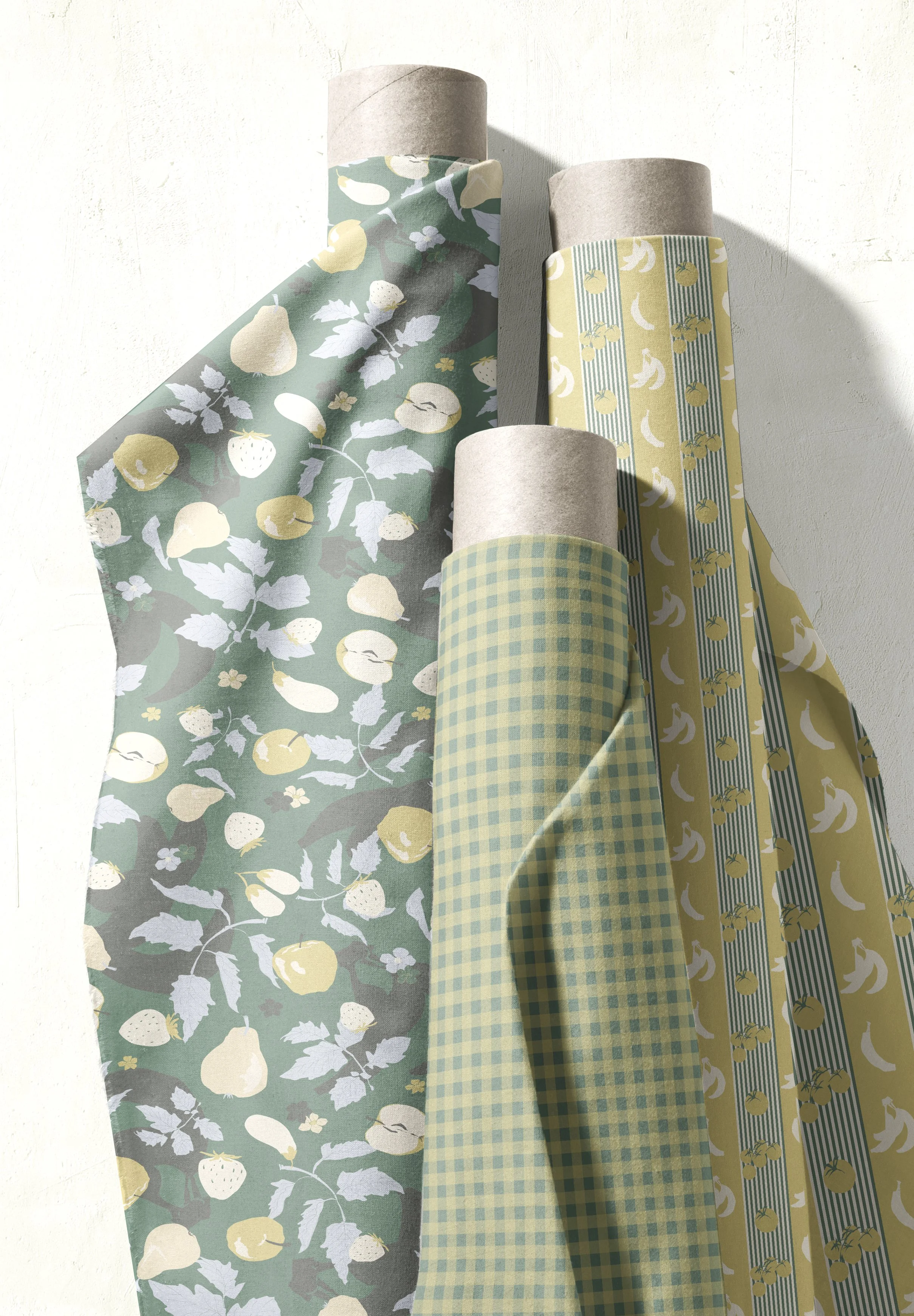 Four rolls of decorative paper with fruit patterns leaning against a light-colored wall.