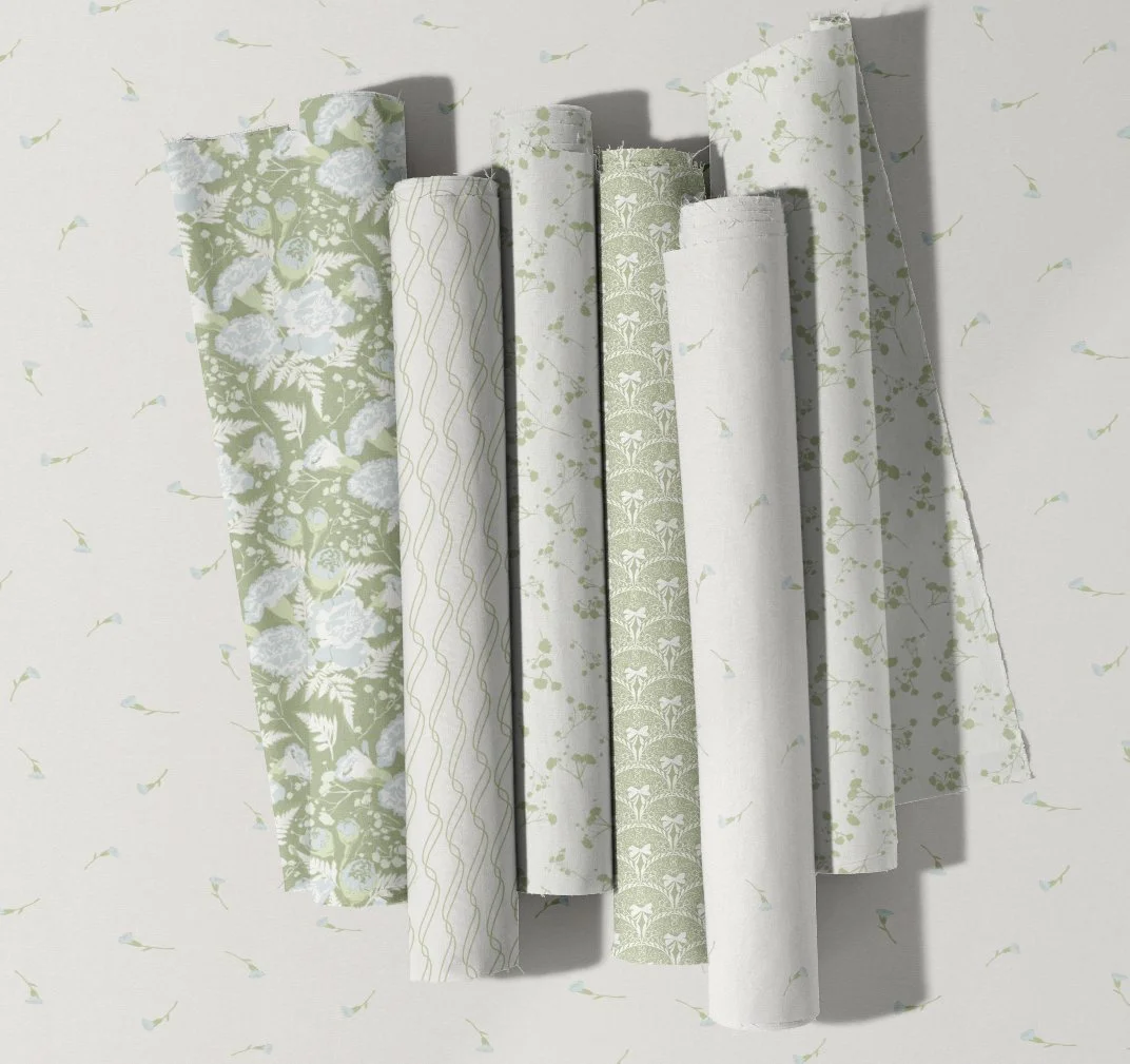 A collection of six rolls of wallpaper with various green and white floral and nature-inspired patterns, arranged vertically against a wall with matching wallpaper.