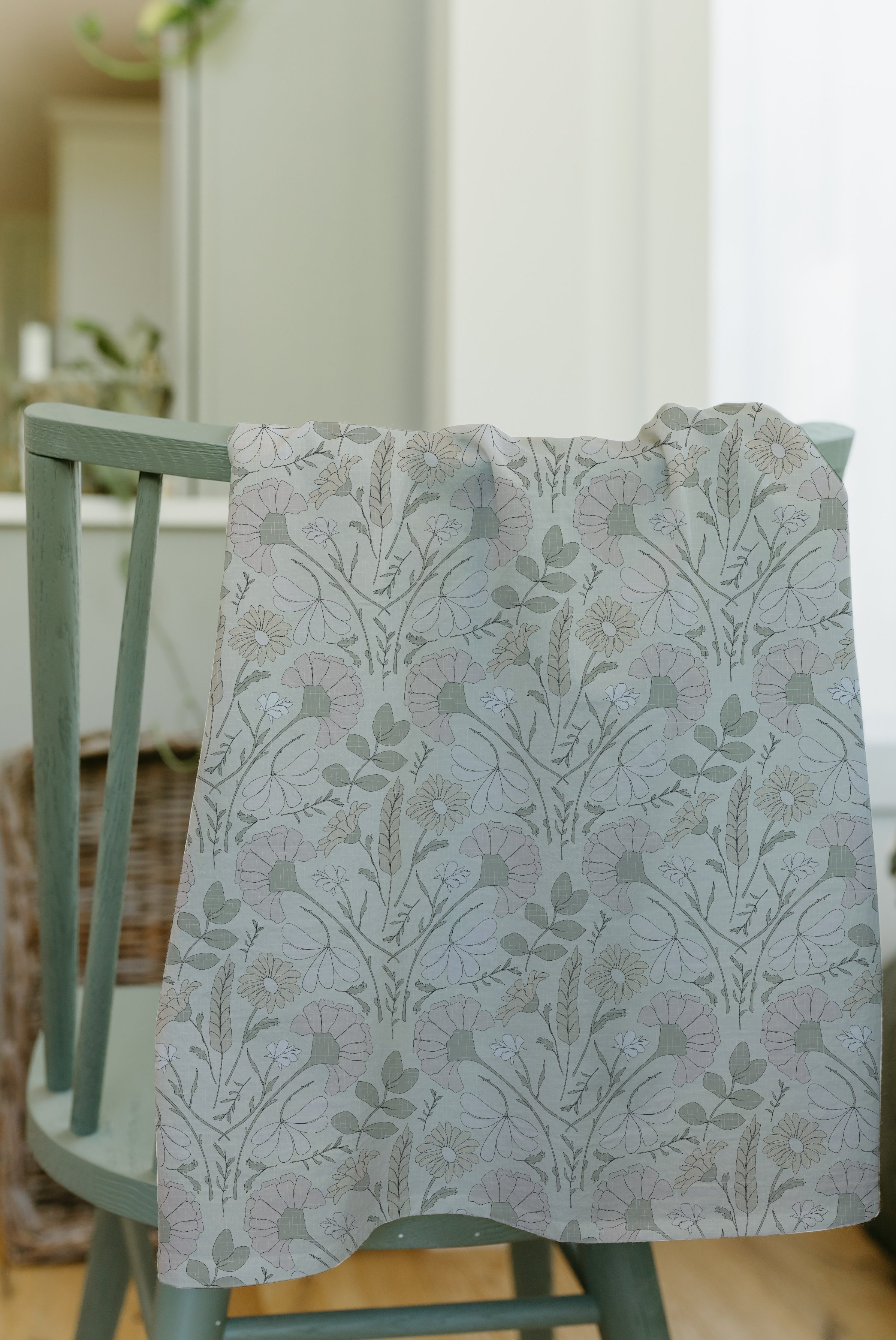 A wooden chair with a floral patterned cloth hanging over the backrest in a sunlit room.