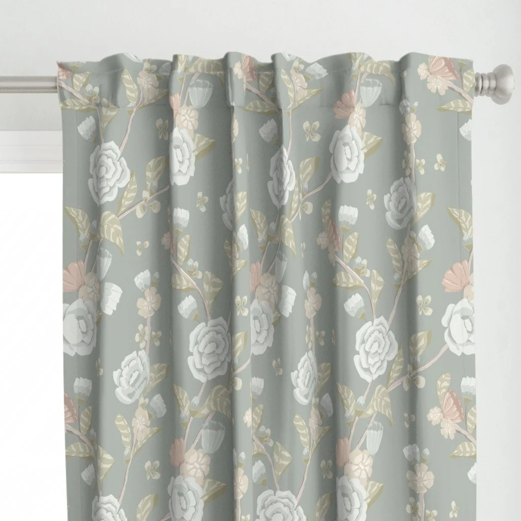 Light blue floral curtain with white, pink, and green pattern hanging on a white curtain rod.
