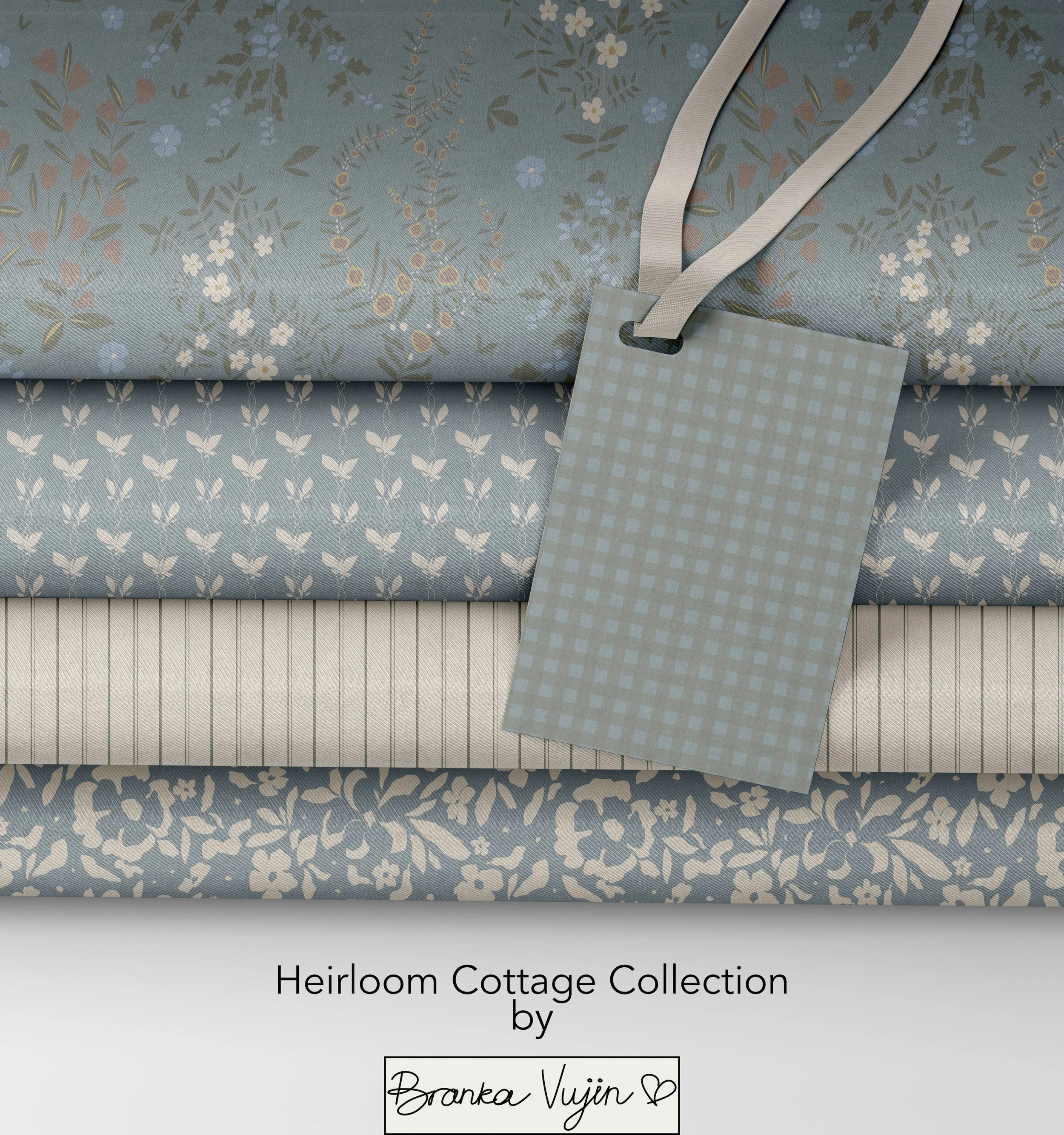 Close-up of fabric with floral and leaf pattern, accompanied by a fabric tag with beige ribbon. The text on the tag reads 'Heirloom Cottage Collection by Branka Vujin' with a decorative heart.