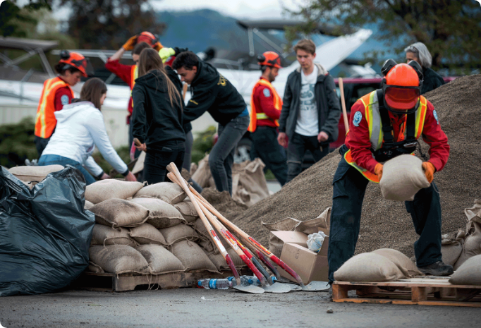 Emergency responders and volunteers work together to move sandbags and supplies at a disaster relief site.