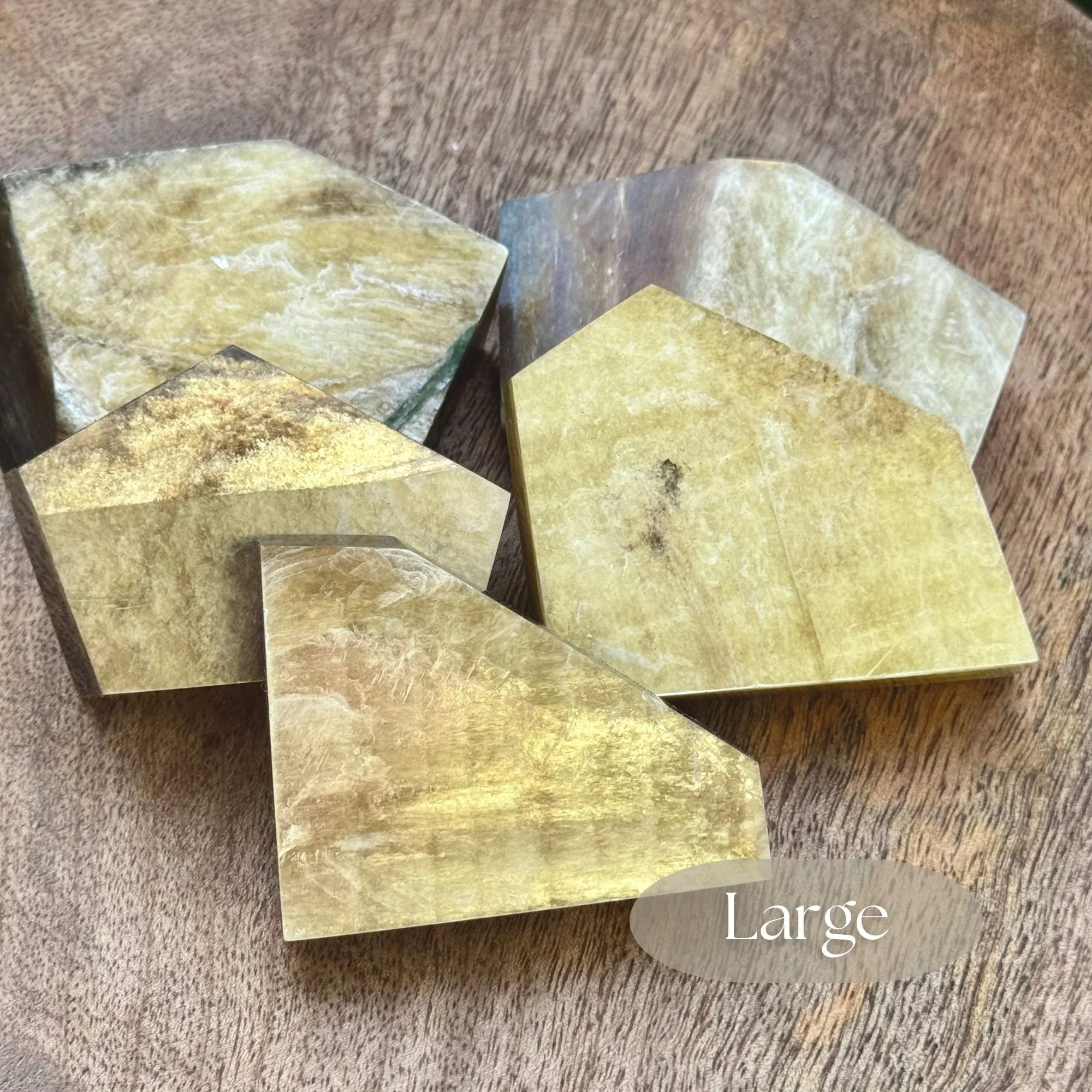 Close up of Various pieces in Large size approximately 2.5 inches by 2 inches of Muscovite or Golden Mica with natural shimmering golden hues and shine on wooden dish with green bush in background