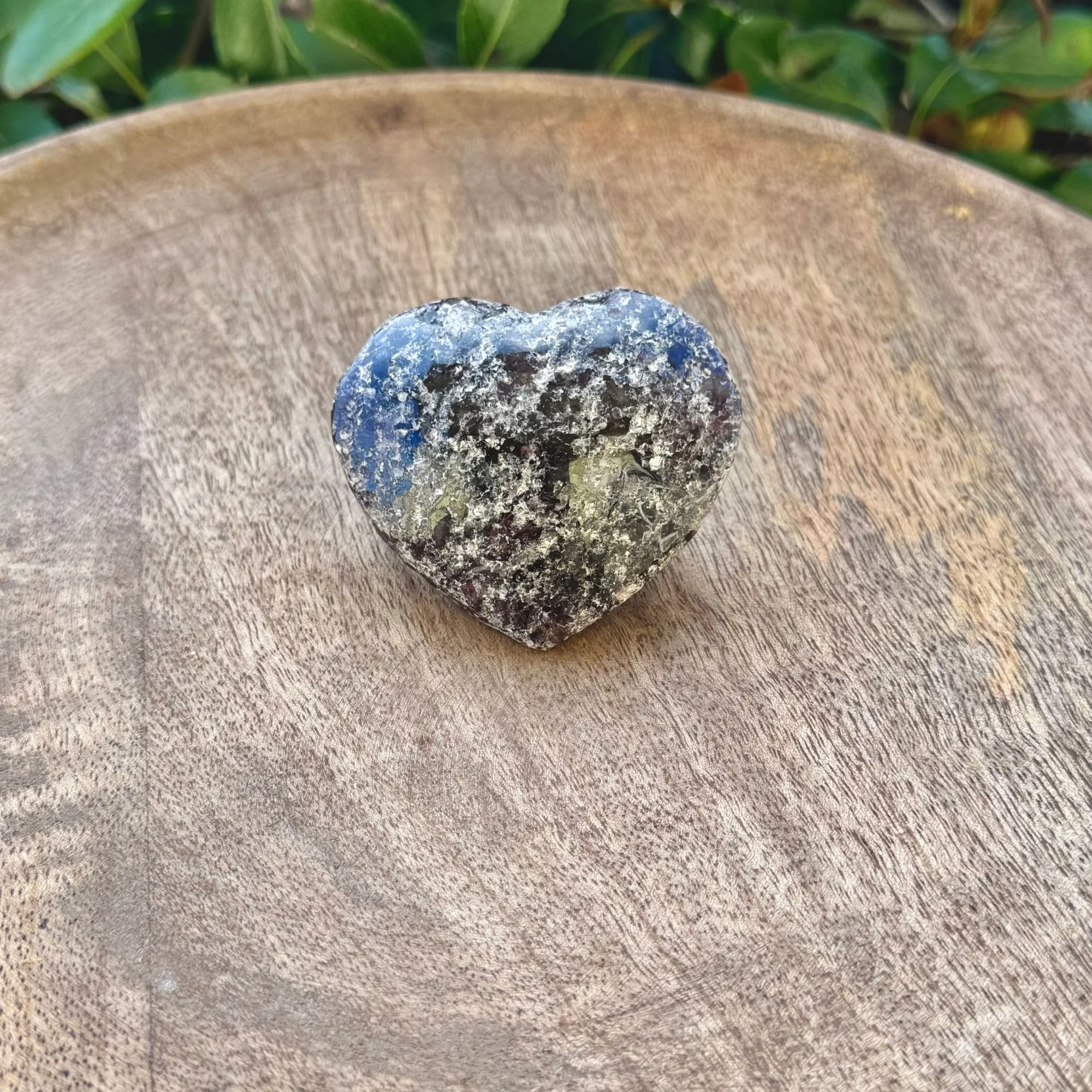 Deep red Garnet Heart Shaped carving in a rough texture not polished on wooden dish