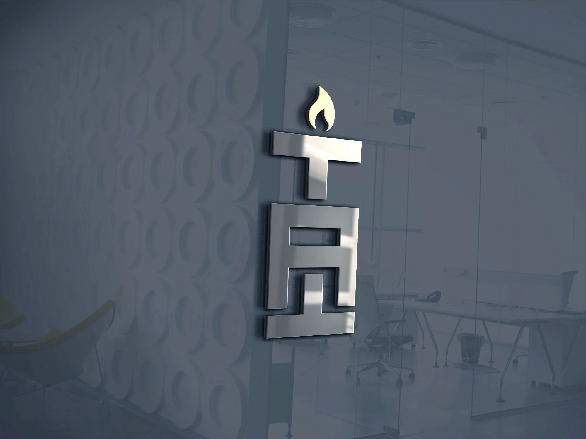 A modern office conference room with a glass wall featuring a metallic logo of a torch with a flame. The room contains tables, chairs, and some office equipment visible in the background.