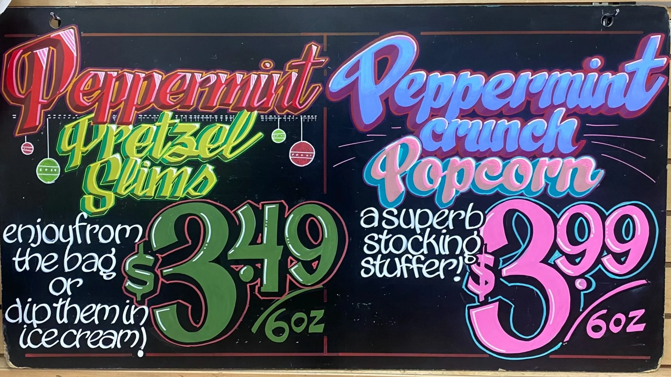 Colorful end-cap sign advertising peppermint, pretzel, and grilled cheese for $3.49, and peppermint crunch popcorn for $3.99, with playful decorations and handwriting.