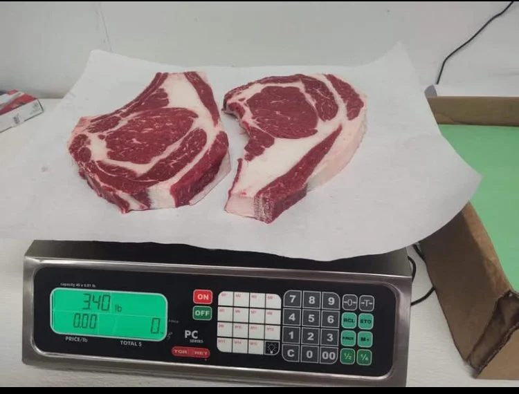Two large raw steaks with marbling on a white paper on a digital scale, showing a weight of 340 pounds.