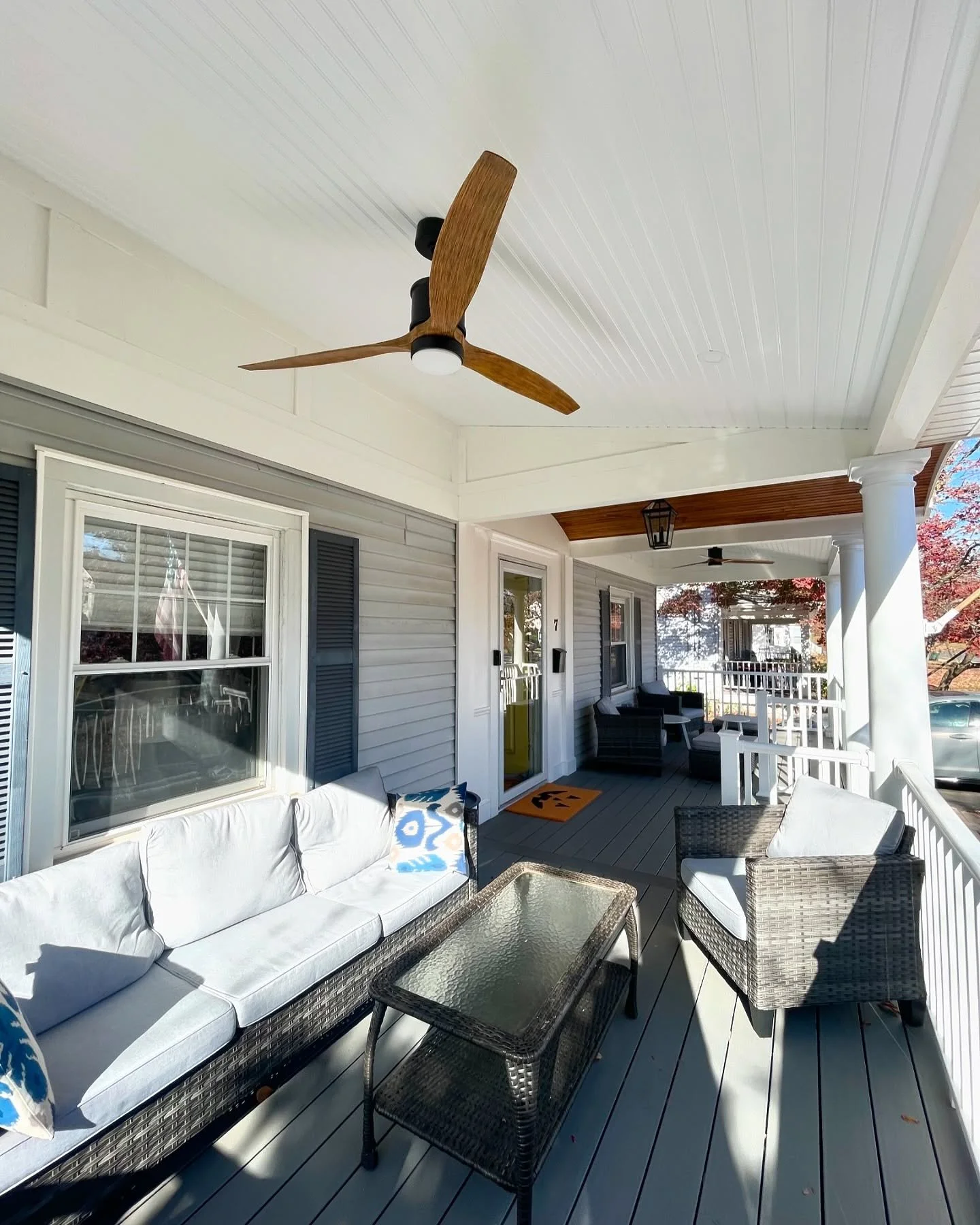 Front porch with outdoor furniture, ceiling fans, and white railing, attached to a house with light gray siding and white trim. Heartwood Renovations. West Hartford, CT