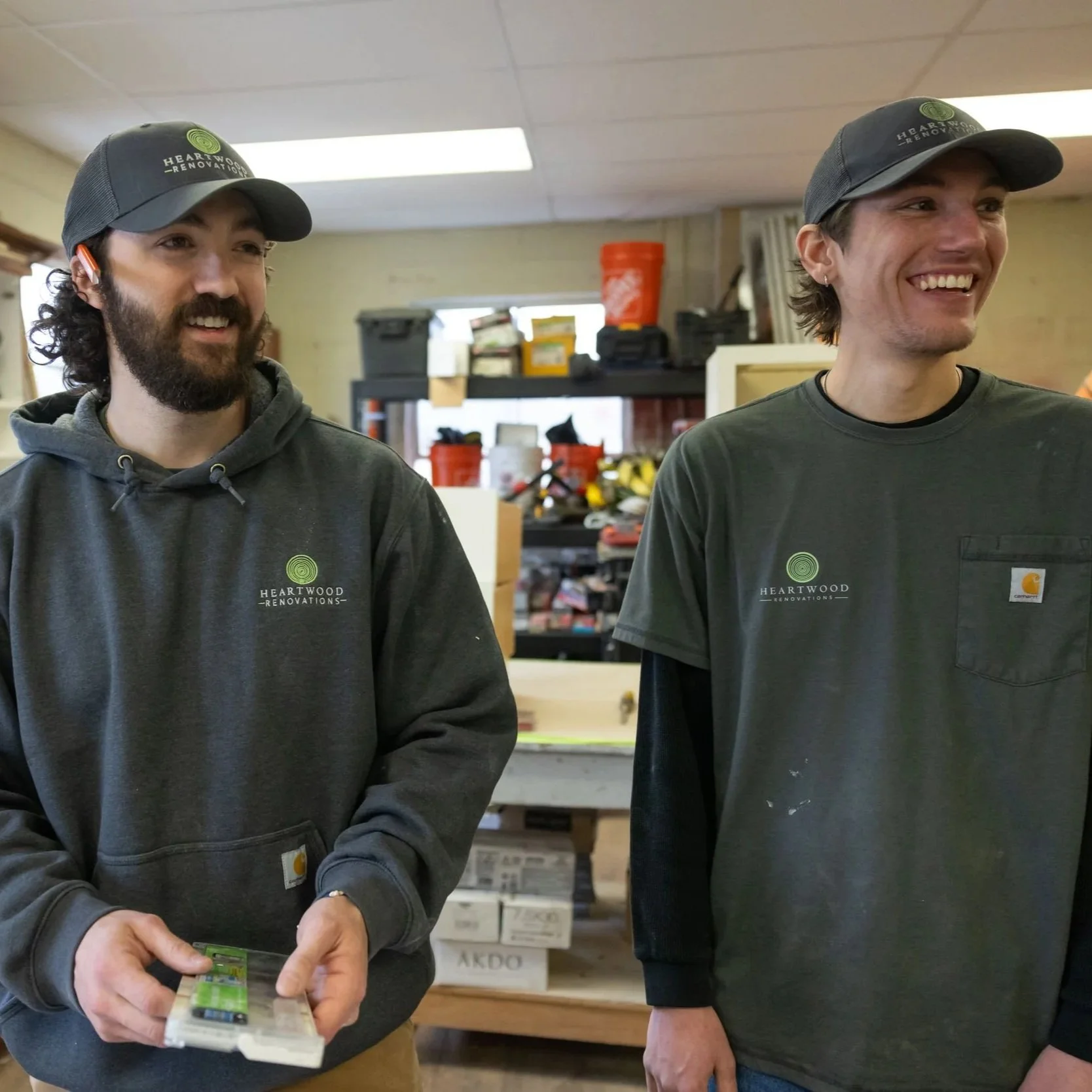 Two Heartwood Renovations carpenters smiling while working together in the shop