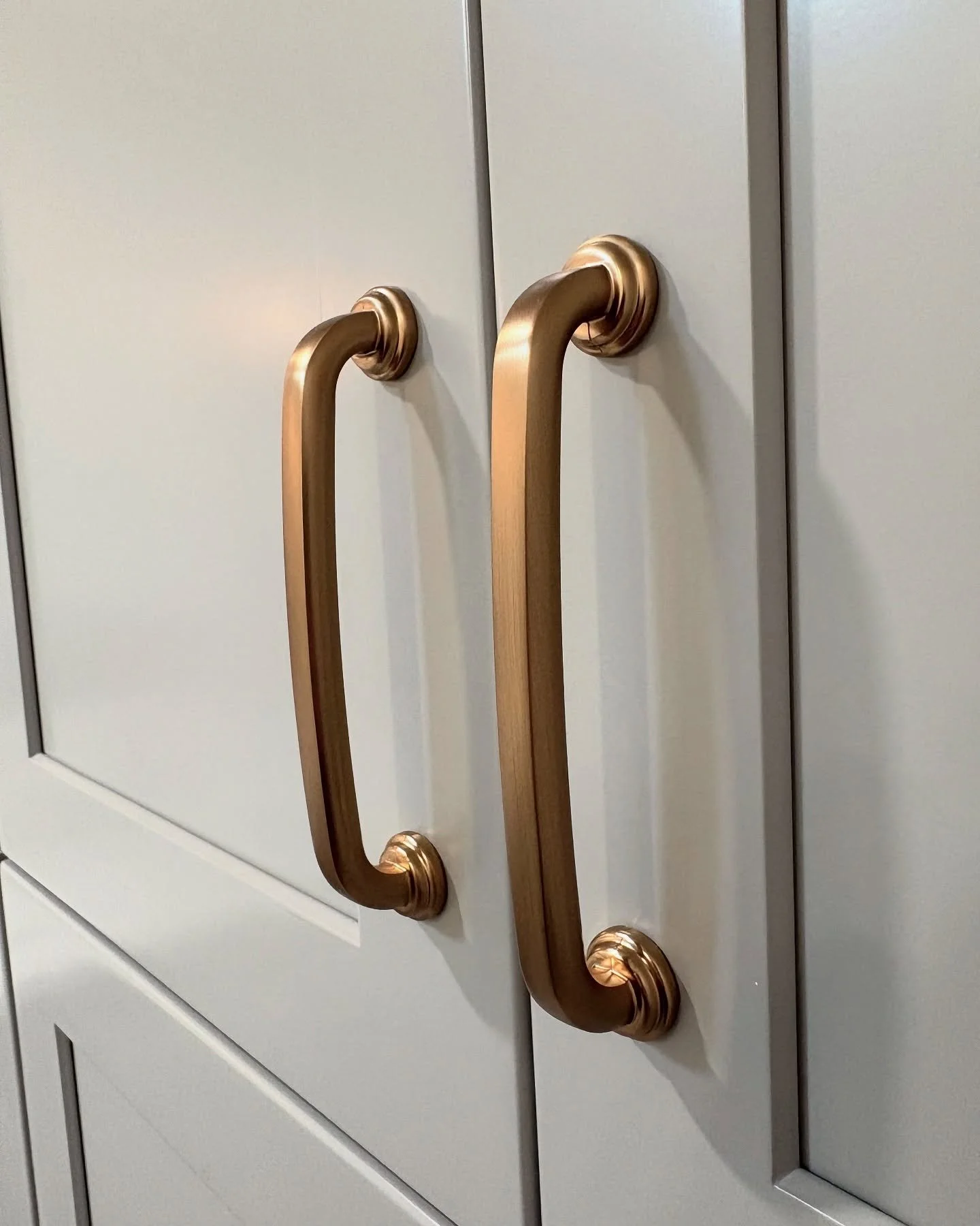 Close-up of two cabinet doors with bronze-colored handles mounted vertically. Heartwood Renovations. West Hartford, CT