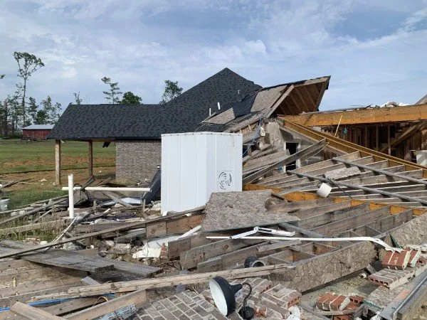 Damaged house with collapsed roof and scattered debris after a storm or collapse.