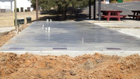 Freshly poured concrete slab with exposed rebar and construction markings on a construction site.