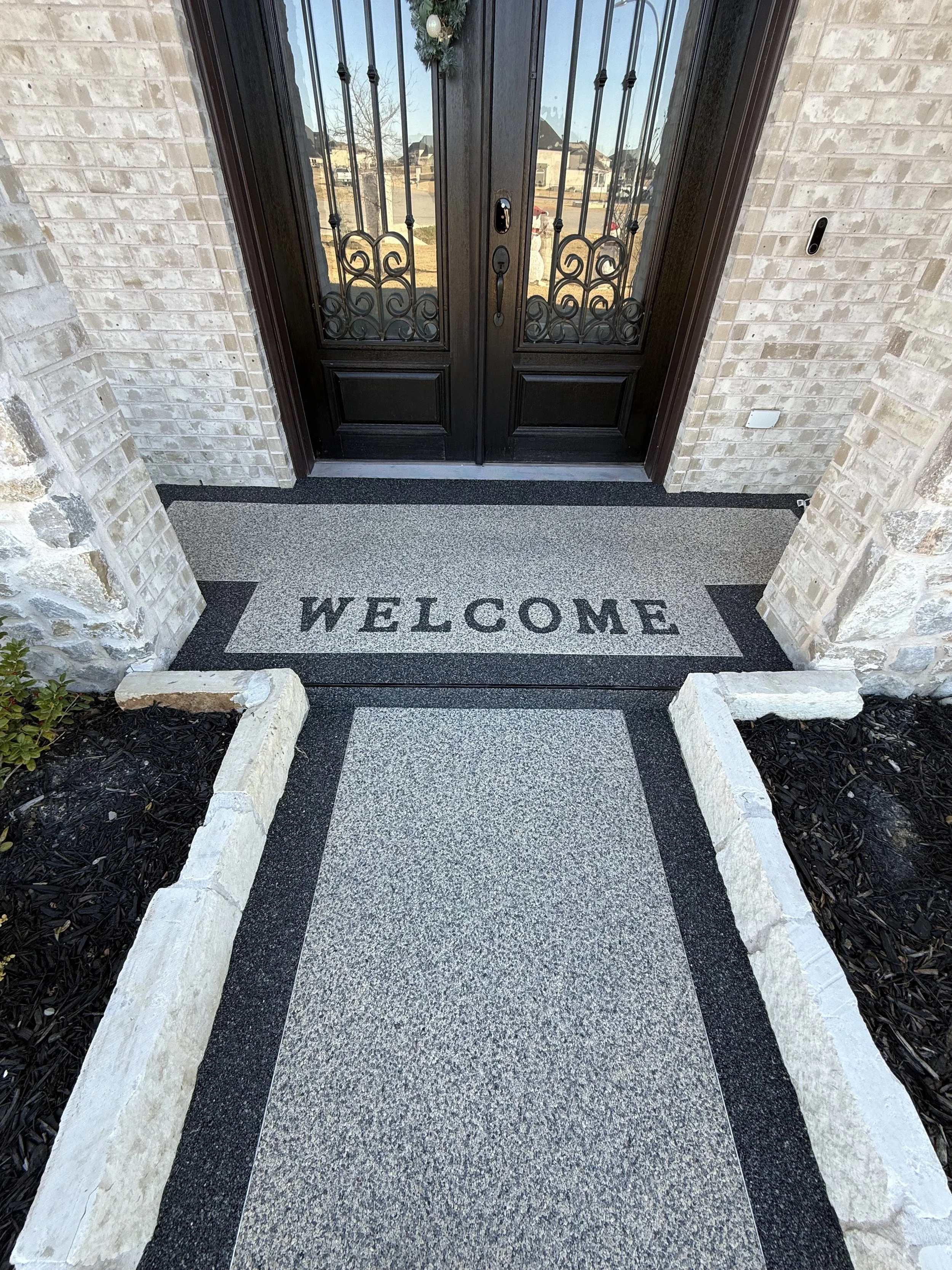Front door with a welcome mat and a concrete walkway leading to the entrance.