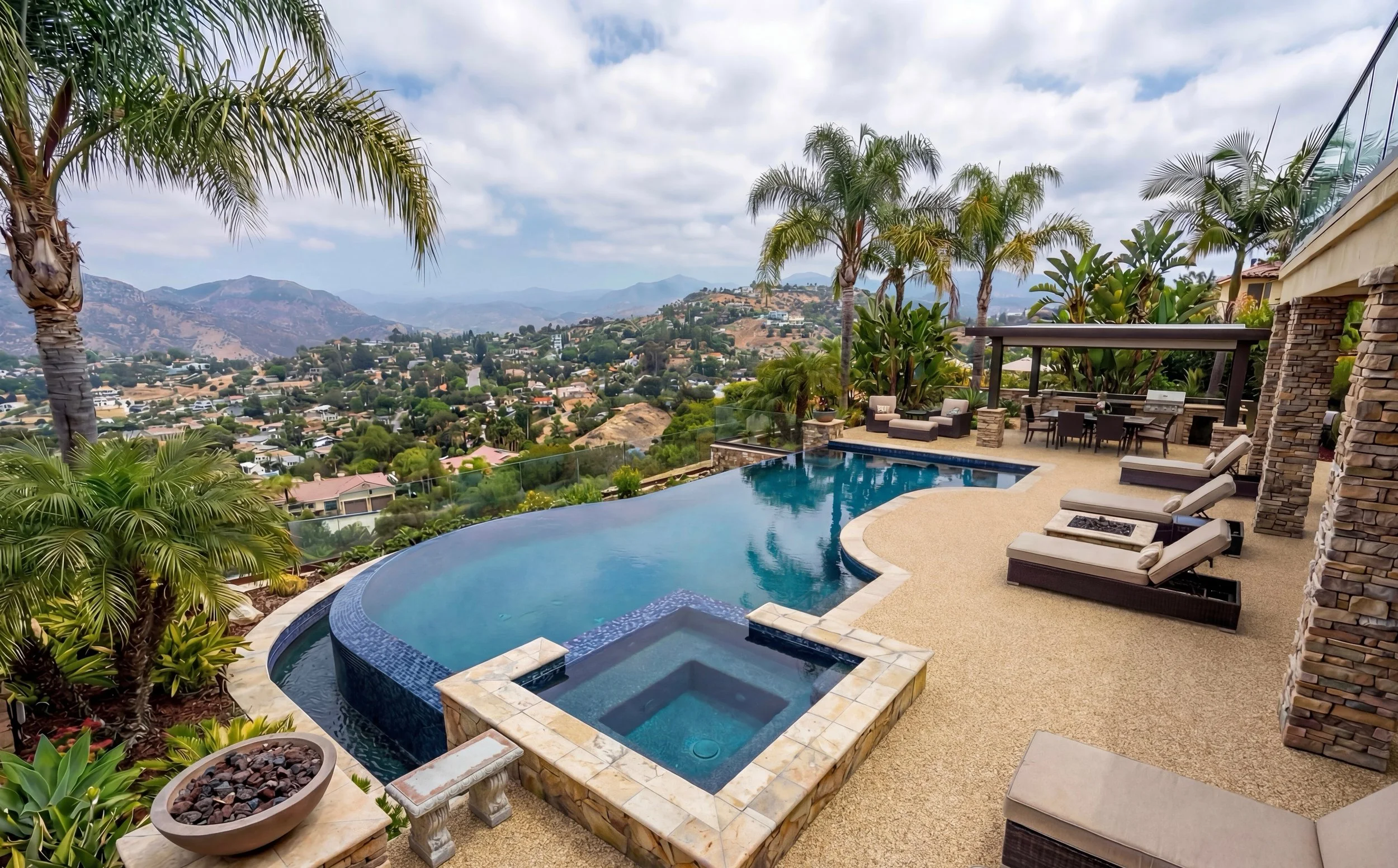 Luxury backyard with swimming pool and mountain view, lounge chairs, outdoor dining table, and landscaping with palm trees and plants.