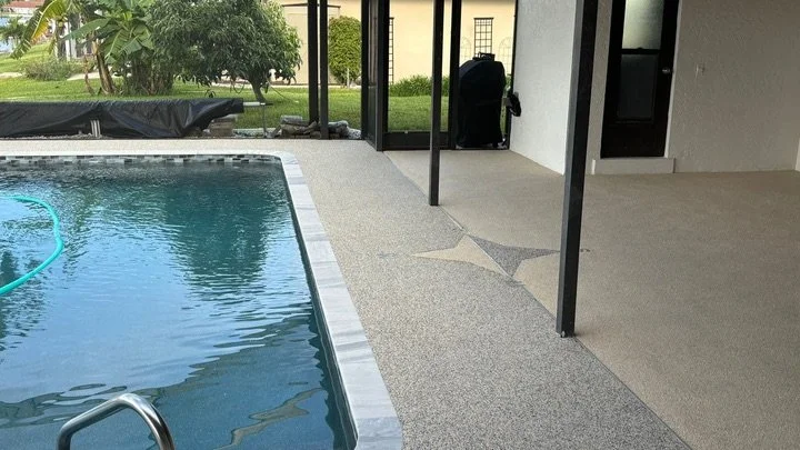 Covered patio area beside a swimming pool with a star design on the floor, some furniture, and an open sliding glass door leading outside.
