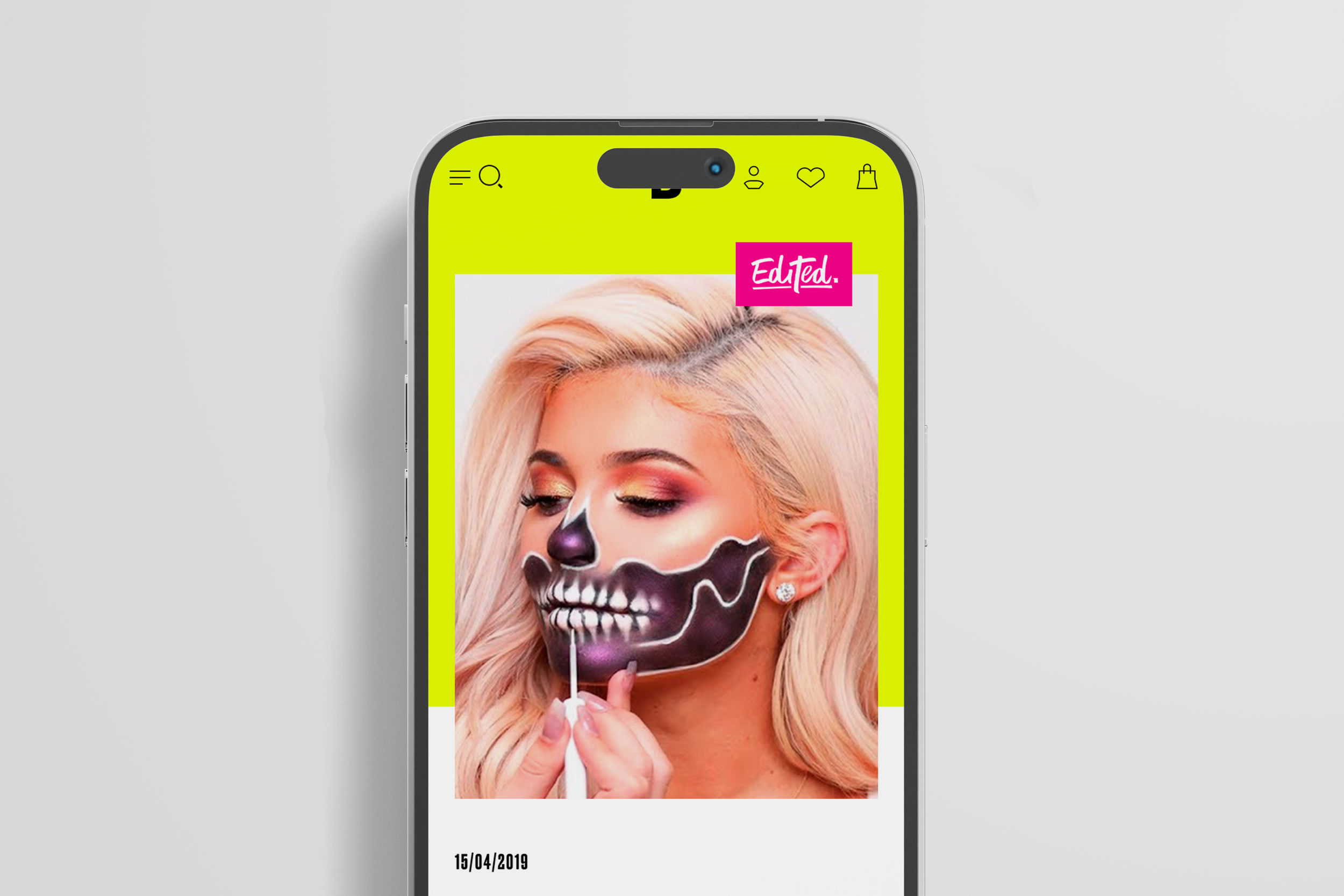 A woman with blonde hair and earrings having skeleton makeup painted on her face, with the top part of the makeup being black and the lower part being white, while she is painting her face black with a brush.