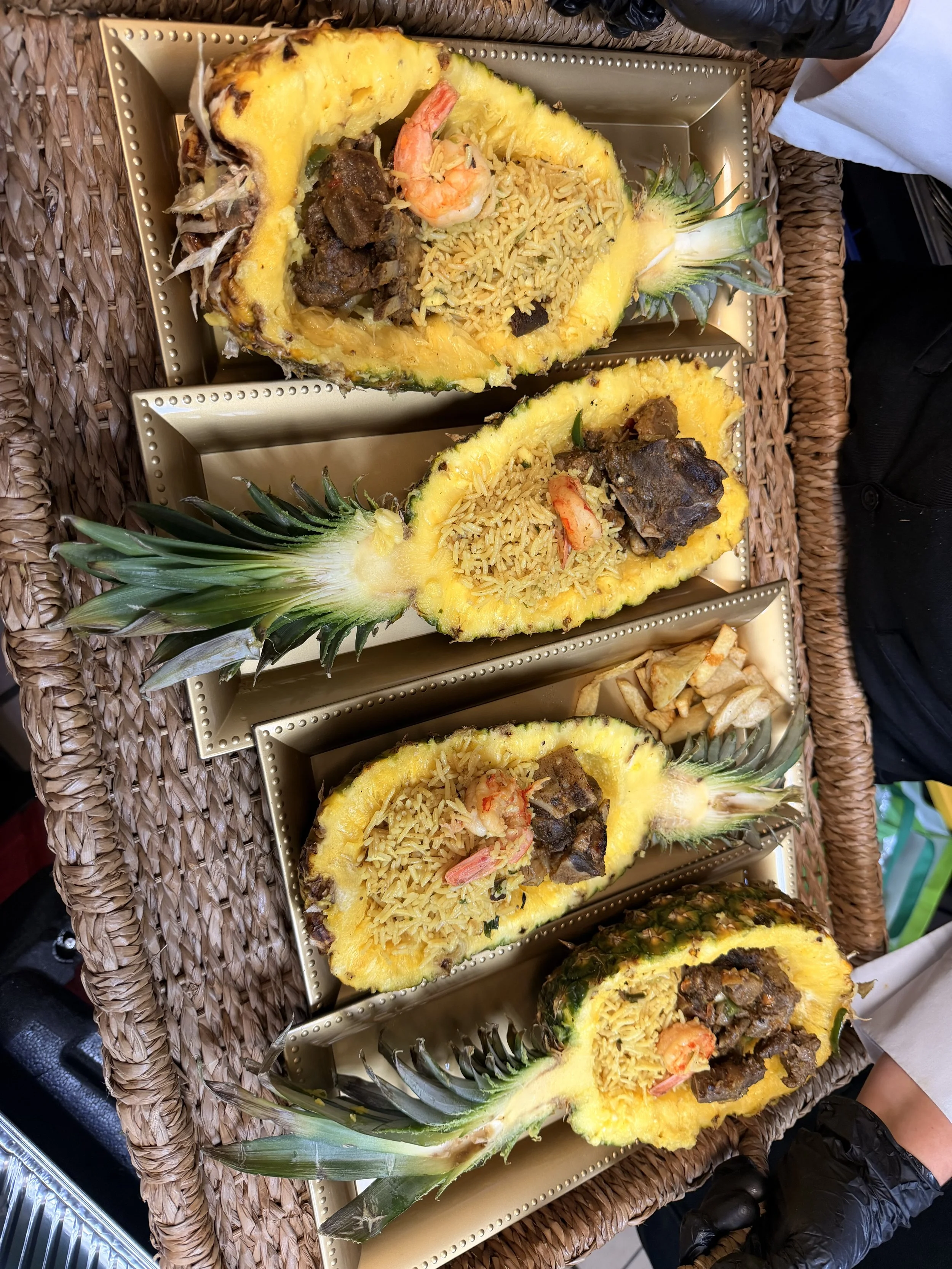 Halved pineapples filled with rice, shrimp, beef, and vegetables, served on gold-colored trays