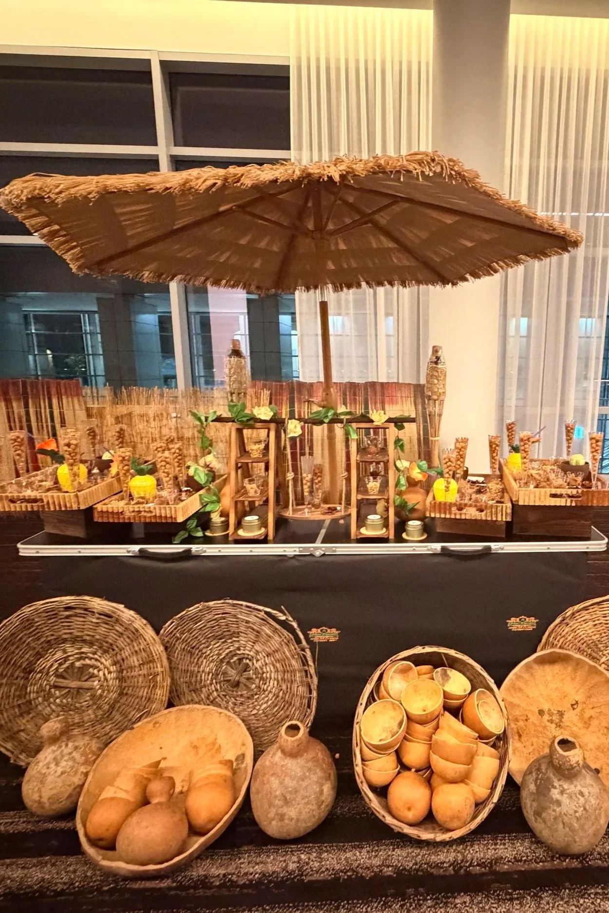 Display of traditional African woven baskets, clay pots, and handcrafted items underneath a bamboo parasol.