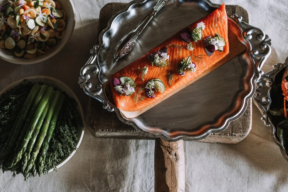 Salmon fillet garnished with herbs and edible flowers on silver platter