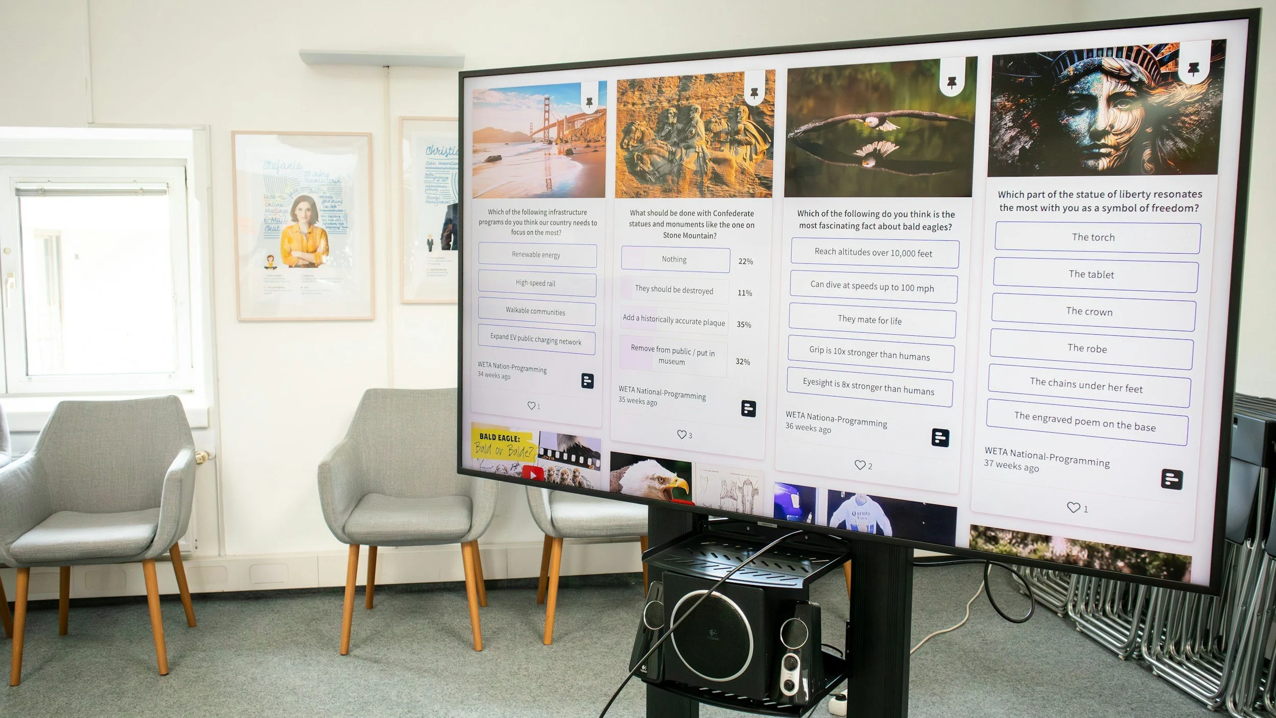 Large digital screen displaying multiple-choice questions with images, in a room with chairs and framed posters on the wall.