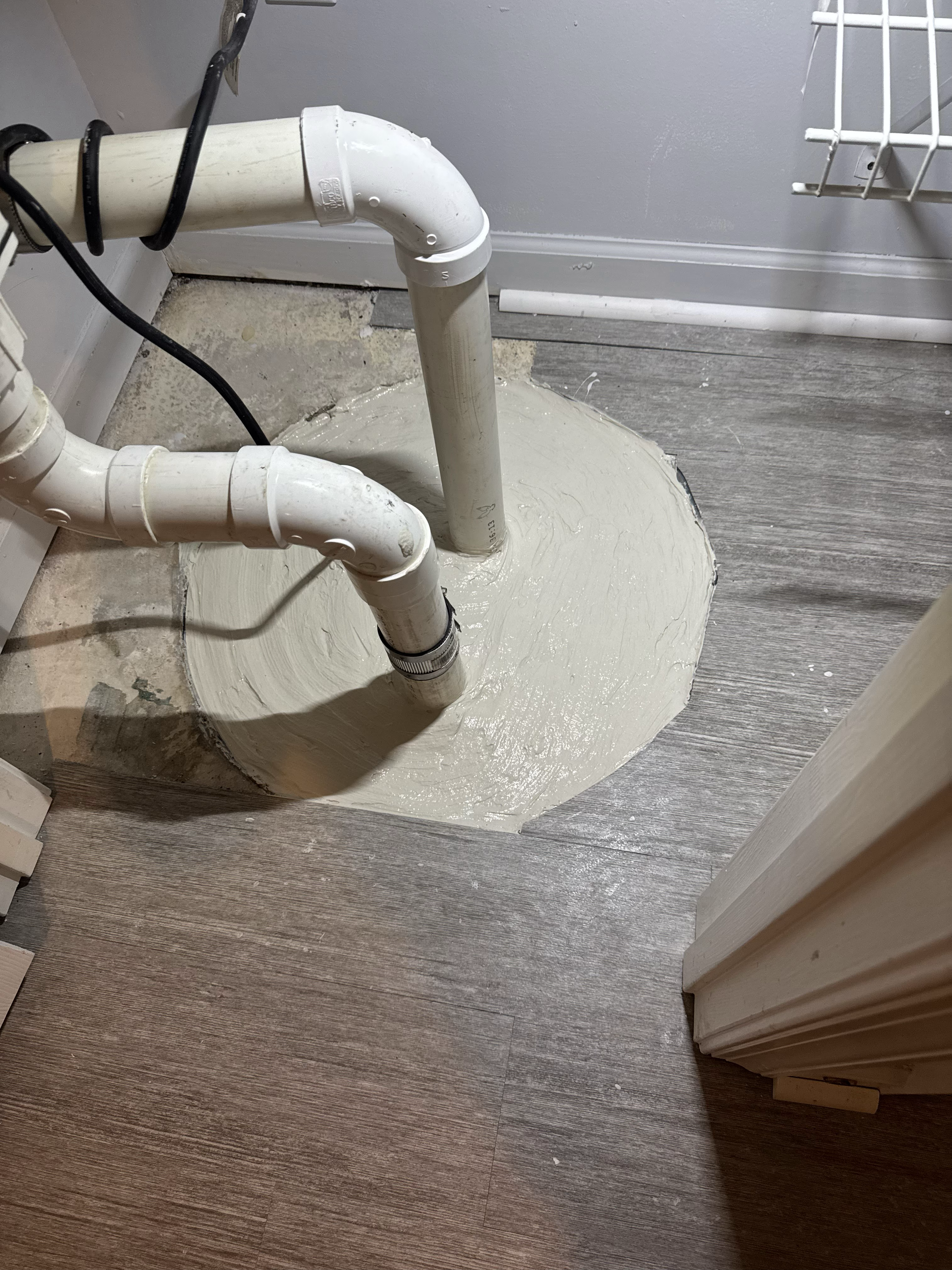 Pipes protruding from the floor with a wet, fresh layer of sealant or paint around the base, indicating recent plumbing work.