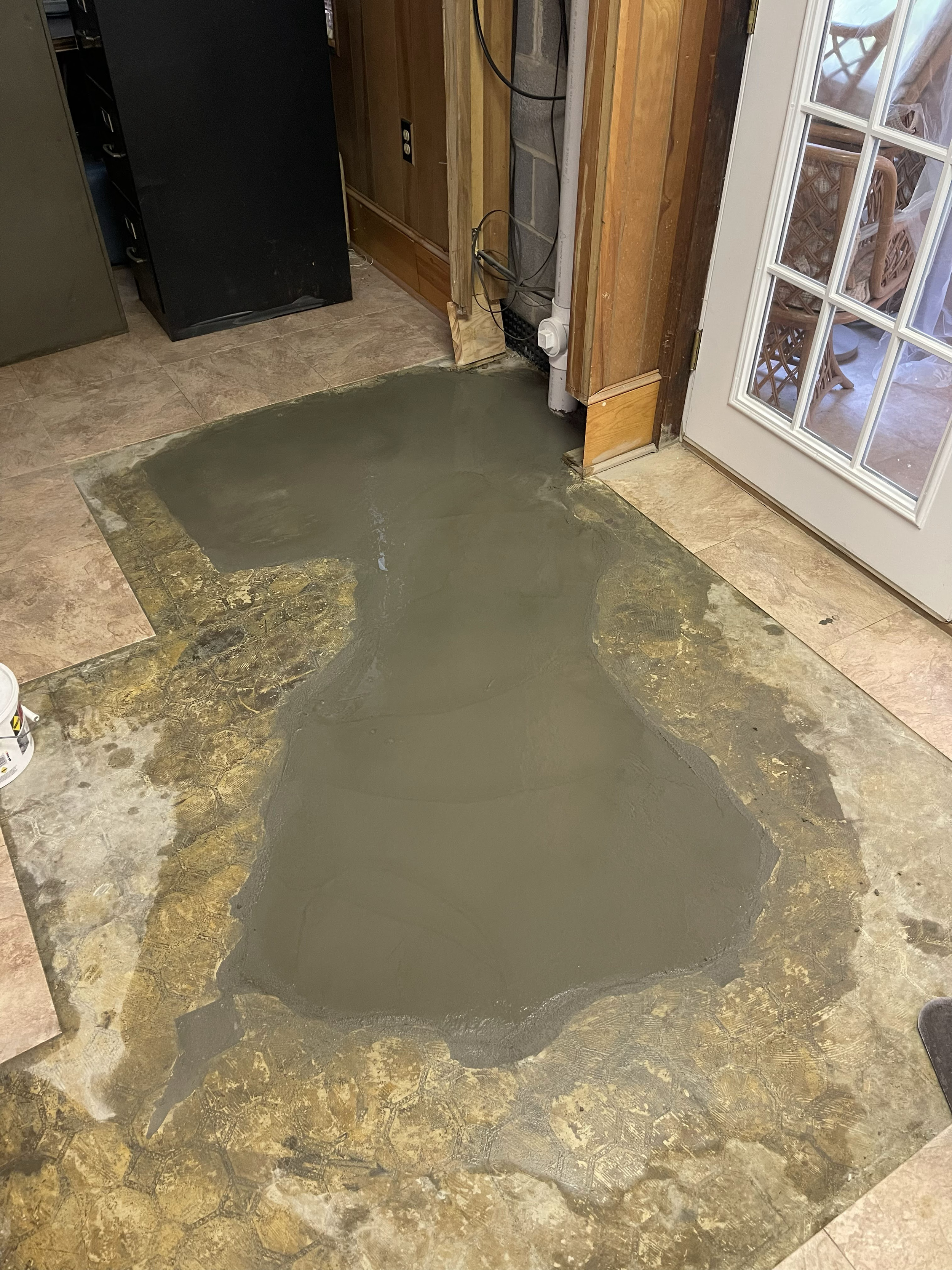 Floor with freshly poured concrete area indoors near a door with glass panes.