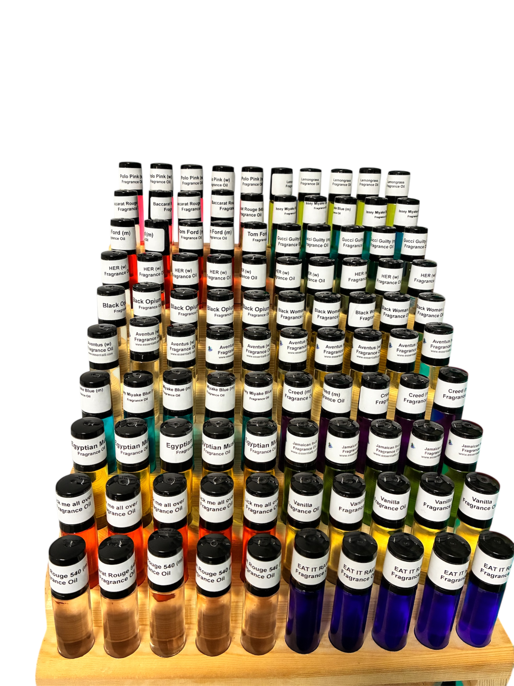 Display of multiple small bottles of fragrance oils arranged in rows on a wooden stand, each labeled with different scent names such as 'Polo Pink', 'Black Opium', 'Vanilla', and 'Rouge 540'.