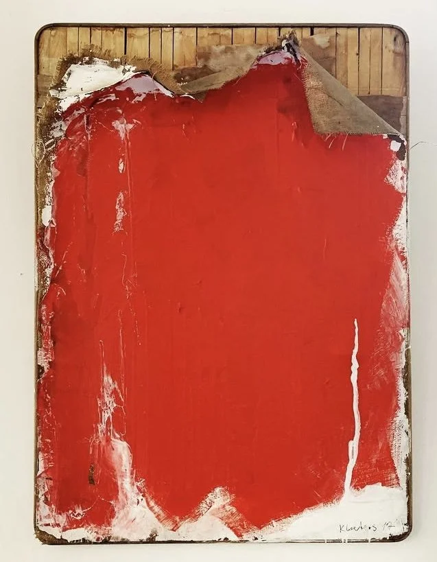 An abstract painting with bold red paint on a canvas, with rough edges and some white and brown accents.