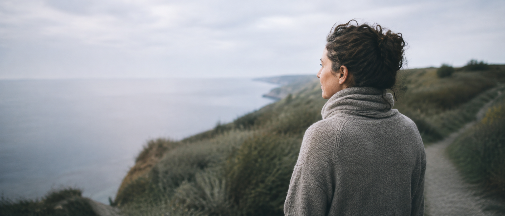 Person pausing quietly outdoors in soft morning light, representing stillness and recovery from burnout
