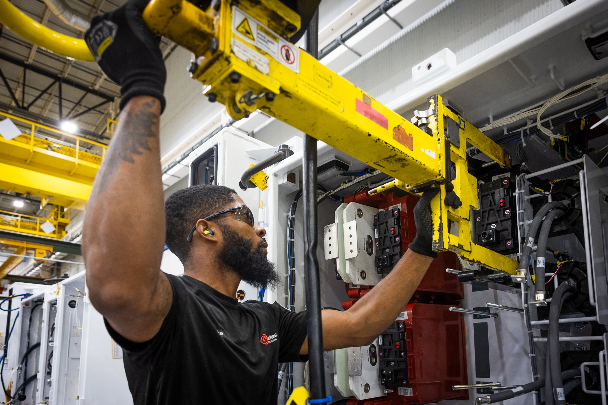 Industrial photography of technician working in a Dallas manufacturing facility wearing safety eye wear and ear protection.