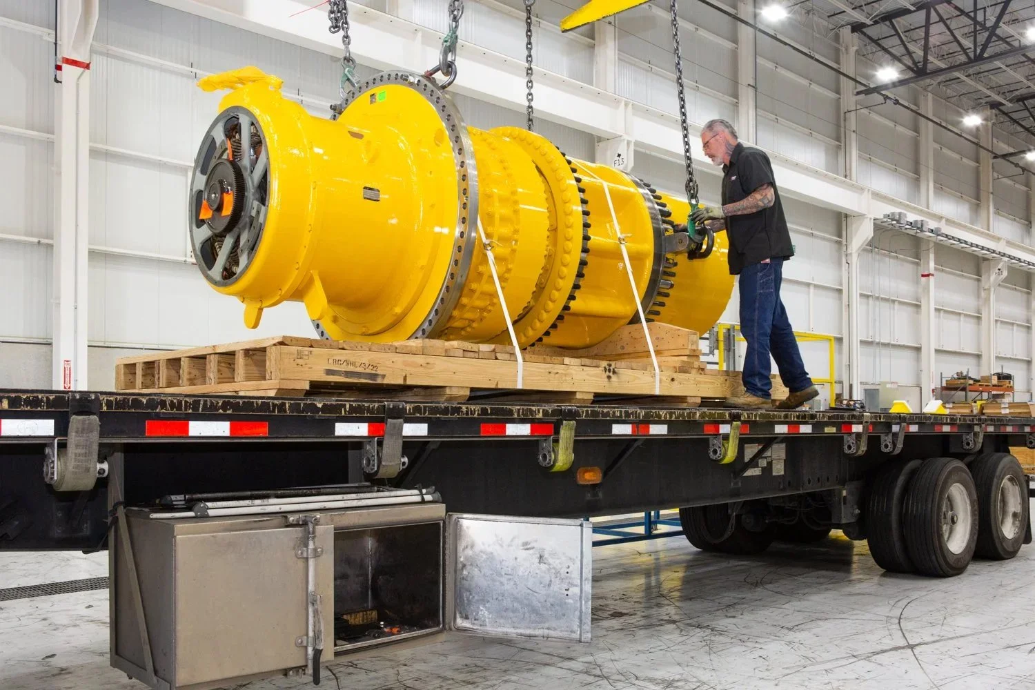 A worker in a manufacturing plant loads a motor on to a truck