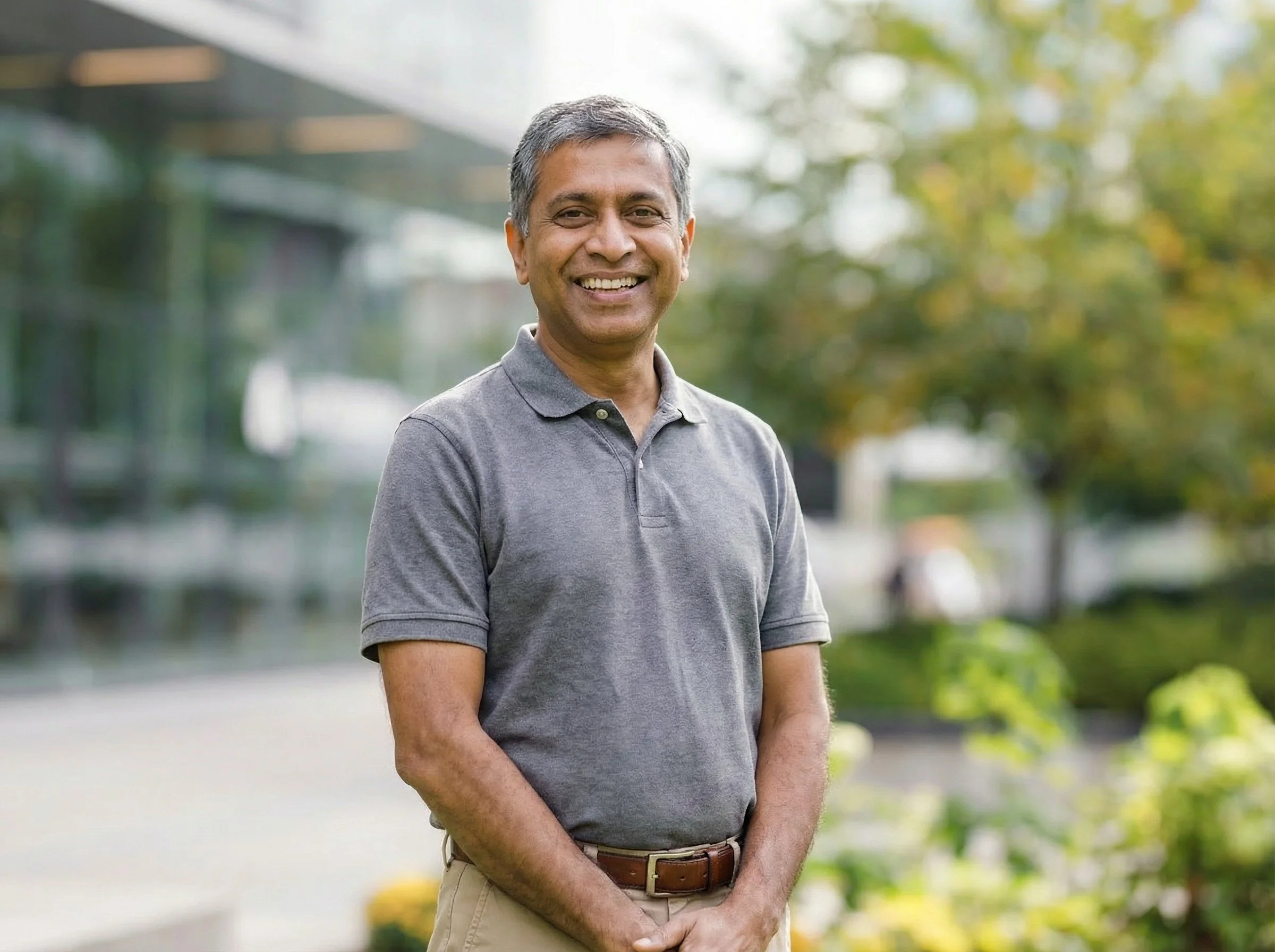 Corporate headshot of an executive photographed on-site outside of Dallas office with trees and a building in the background.