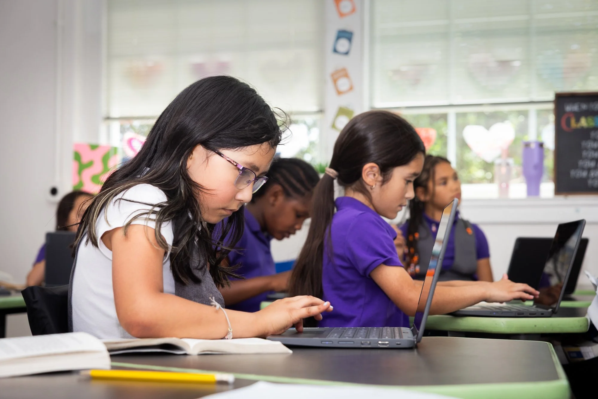 Students working on laptops in a classroom, focused on their screens.