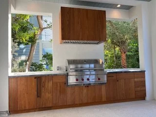 Kitchen with large windows, wooden cabinets, and a stainless steel barbecue grill.