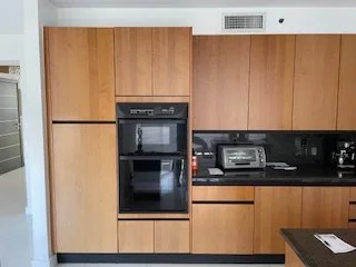 Modern kitchen with wooden cabinets, black countertop, built-in oven, and microwave, with a toaster on the counter.