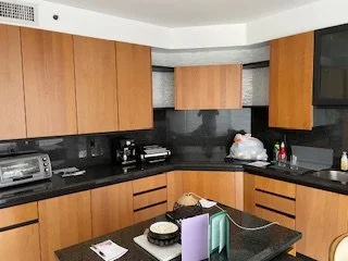 Modern kitchen with wooden cabinets, black countertops, and various small appliances on the counter.