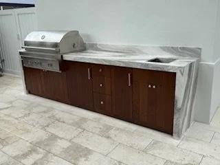 A countertop with a built-in grill or barbecue, alongside cabinets, in an indoor or outdoor kitchen setting.