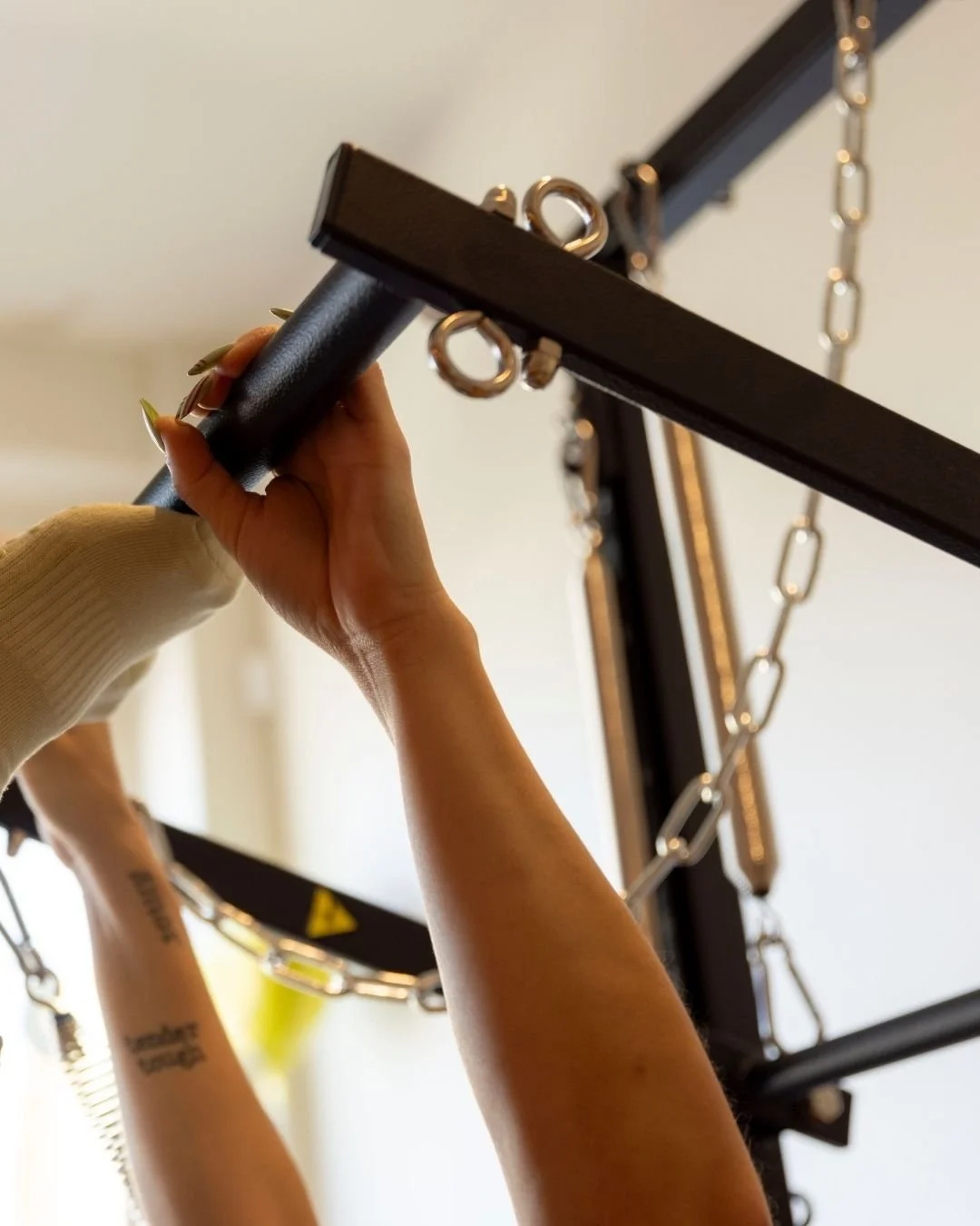 A woman practicing yoga on a Pilates reformer machine in a modern, softly lit fitness studio.