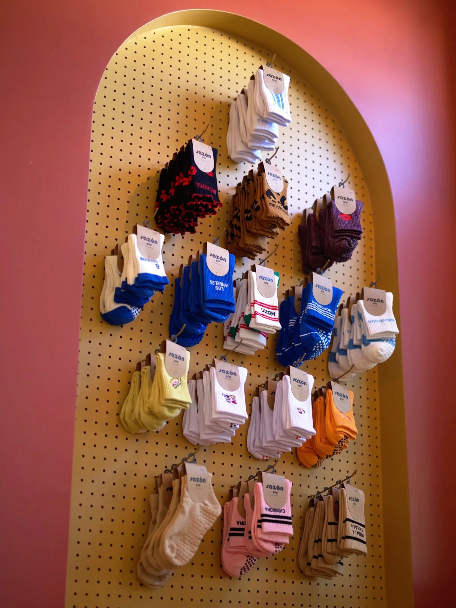 Display of various colorful socks hanging on a pegboard in a retail store.